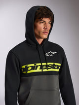 Sudadera con capucha Alpinestars Parallel, estilo streetwear casual con bloques de color, parte superior negra y parte inferior gris plomo, banda amarilla neón en el pecho con el logo de Alpinestars en negro, logo Astars blanco, jersey con capucha y cordón