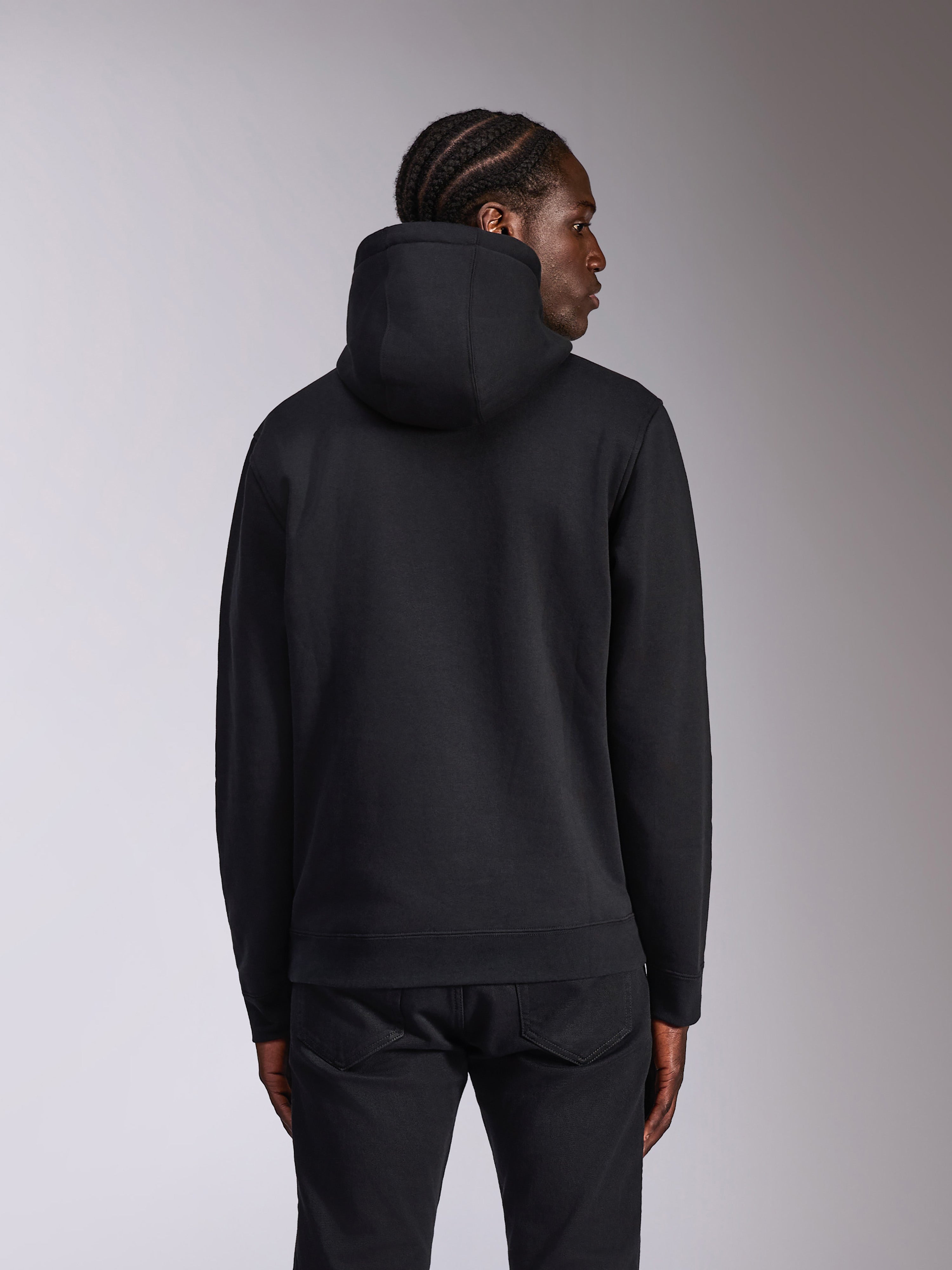 Sudadera Alpinestars Pulse, negra, vista posterior en modelo, ropa casual urbana, sudadera con capucha de diseño negro sólido, puños y dobladillo de canalé, combinada con pantalones negros