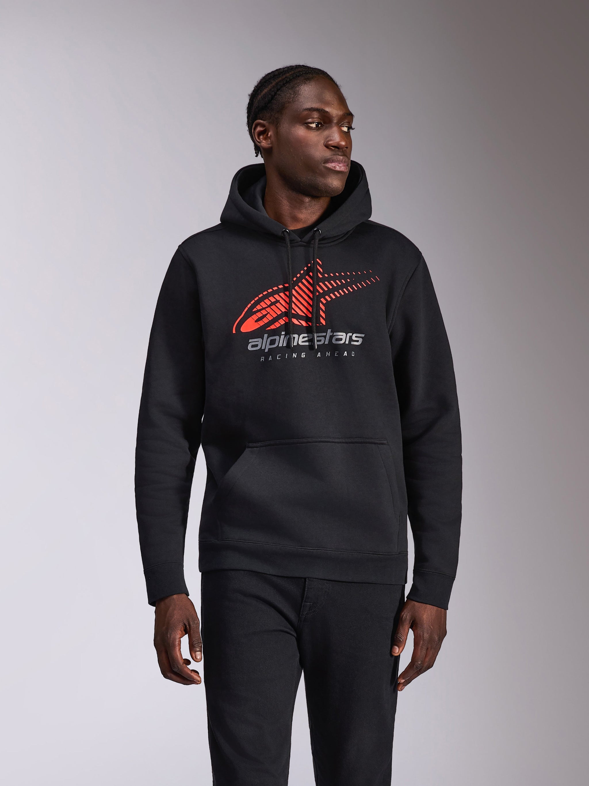 Alpinestars Pulse Hoodie, sudadera informal con capucha, negra con logotipo Astars en rojo y gris con degradado de líneas de velocidad y el texto 'Racing Ahead', capucha con cordón y bolsillo de canguro, estilo urbano inspirado en el motociclismo lucida por un modelo
