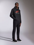 Alpinestars Pulse Hoodie, sudadera negra con capucha, con logotipo Astars en rojo y blanco con degradado de líneas de velocidad y texto Racing Ahead, combinada con pantalones negros a juego y zapatillas, estilo urbano casual inspirado en el automovilismo.