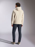 Alpinestars Pulse Hoodie, blanco roto, vista trasera de un hombre con sudadera informal de felpa con capucha, vaqueros oscuros y zapatillas, diseño de ropa deportiva moderna