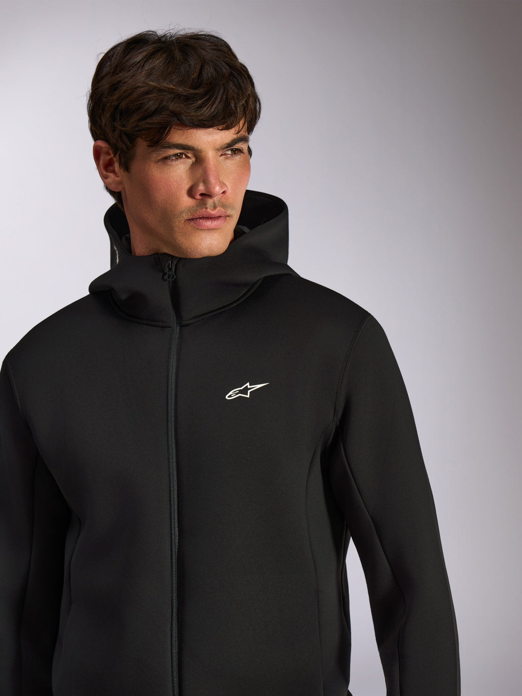 Alpinestars Cypher Hoodie, ropa deportiva casual, sudadera negra con cremallera frontal y logo Astars blanco en el pecho, diseño de capucha de cuello alto, usada por modelo masculino