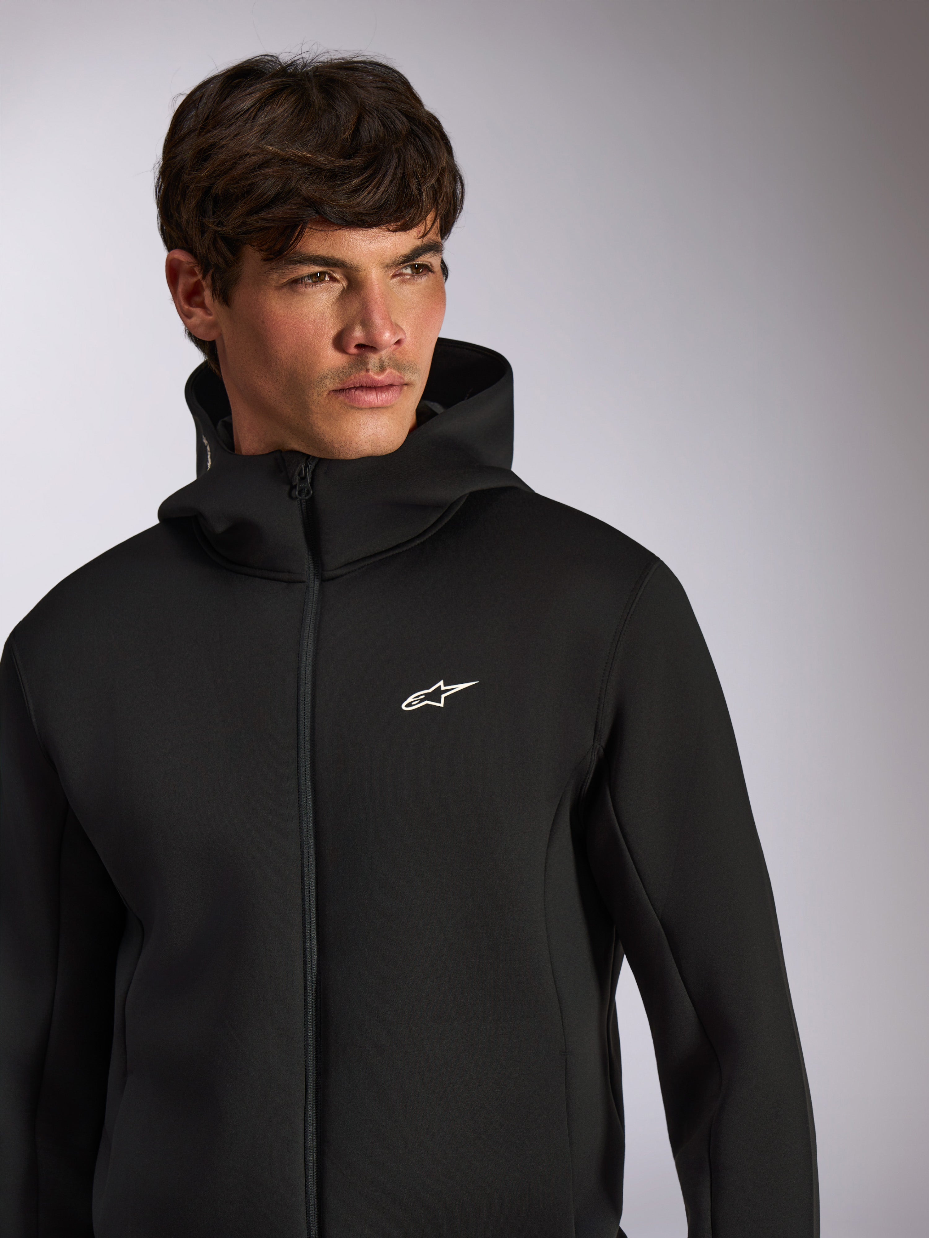 Alpinestars Cypher Hoodie, ropa deportiva casual, sudadera negra con cremallera frontal y logo Astars blanco en el pecho, diseño de capucha de cuello alto, usada por modelo masculino