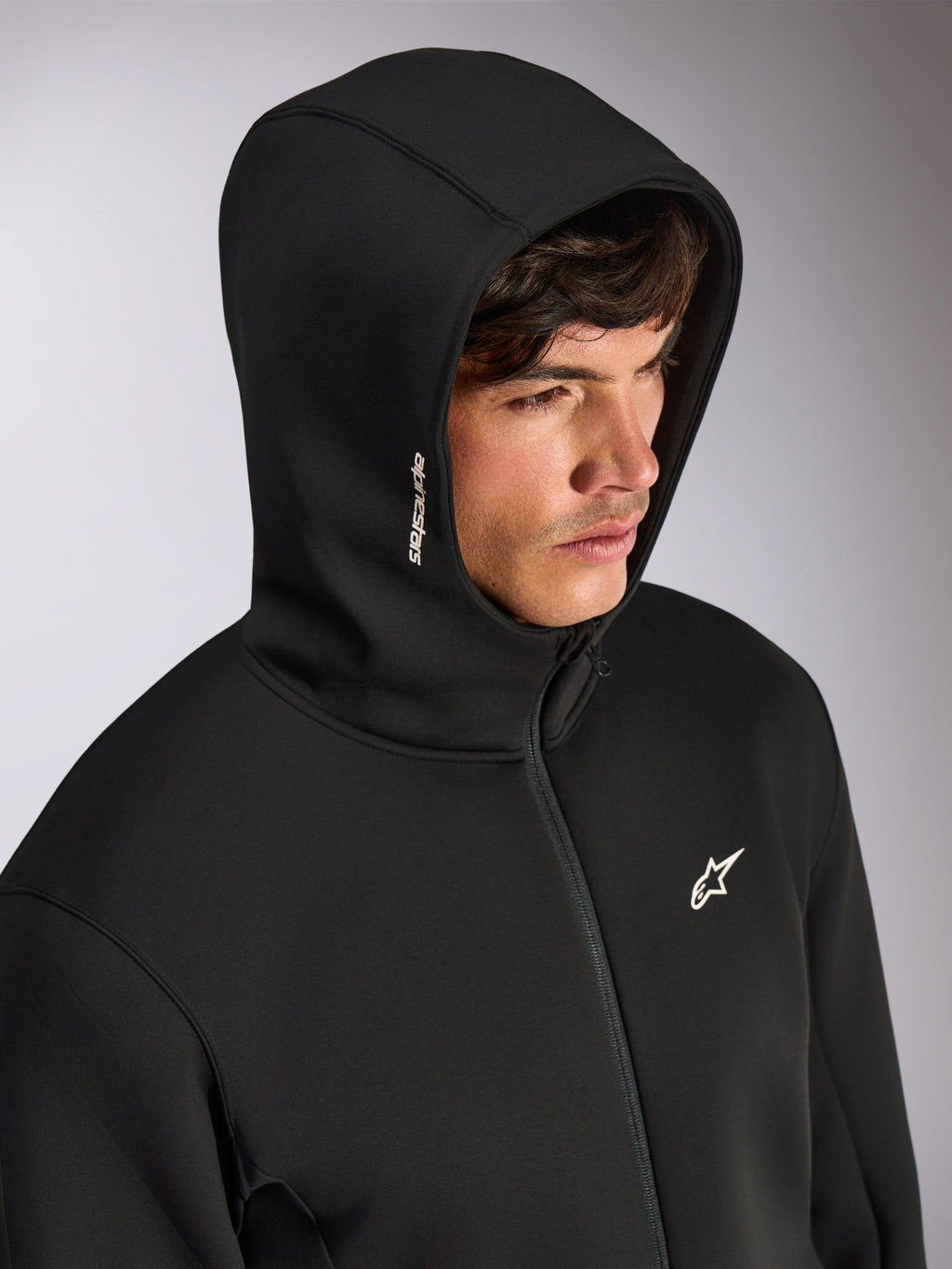 Sudadera con capucha Alpinestars Cypher, sudadera negra con cremallera frontal y capucha de cuello alto, logotipo blanco de Alpinestars en la capucha y logo de estrella en el pecho, ropa urbana casual inspirada en el automovilismo