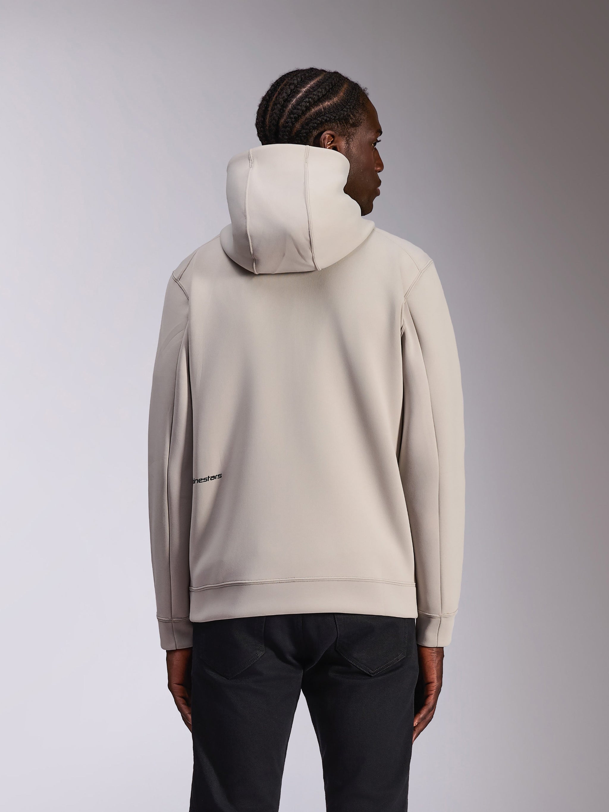 Alpinestars Cypher Hoodie, ropa deportiva casual, gris cemento, vista posterior en modelo, capucha de cuello alto, material de forro polar de doble cara, logotipo minimalista de Alpinestars en la parte inferior de la espalda, combinada con pantalones negros