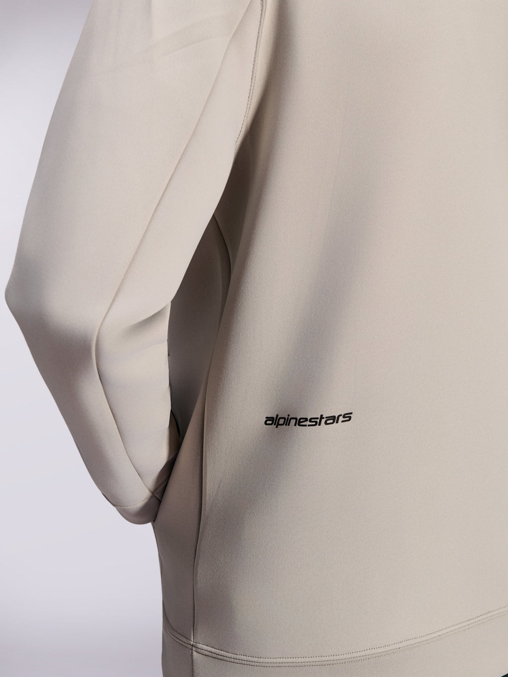 Alpinestars Cypher Hoodie, sudadera con cremallera de forro polar de doble cara, Gris Cemento, primer plano del pequeño logotipo de Alpinestars en la parte inferior de la espalda, detalle del bolsillo en la costura y textura de tejido suave