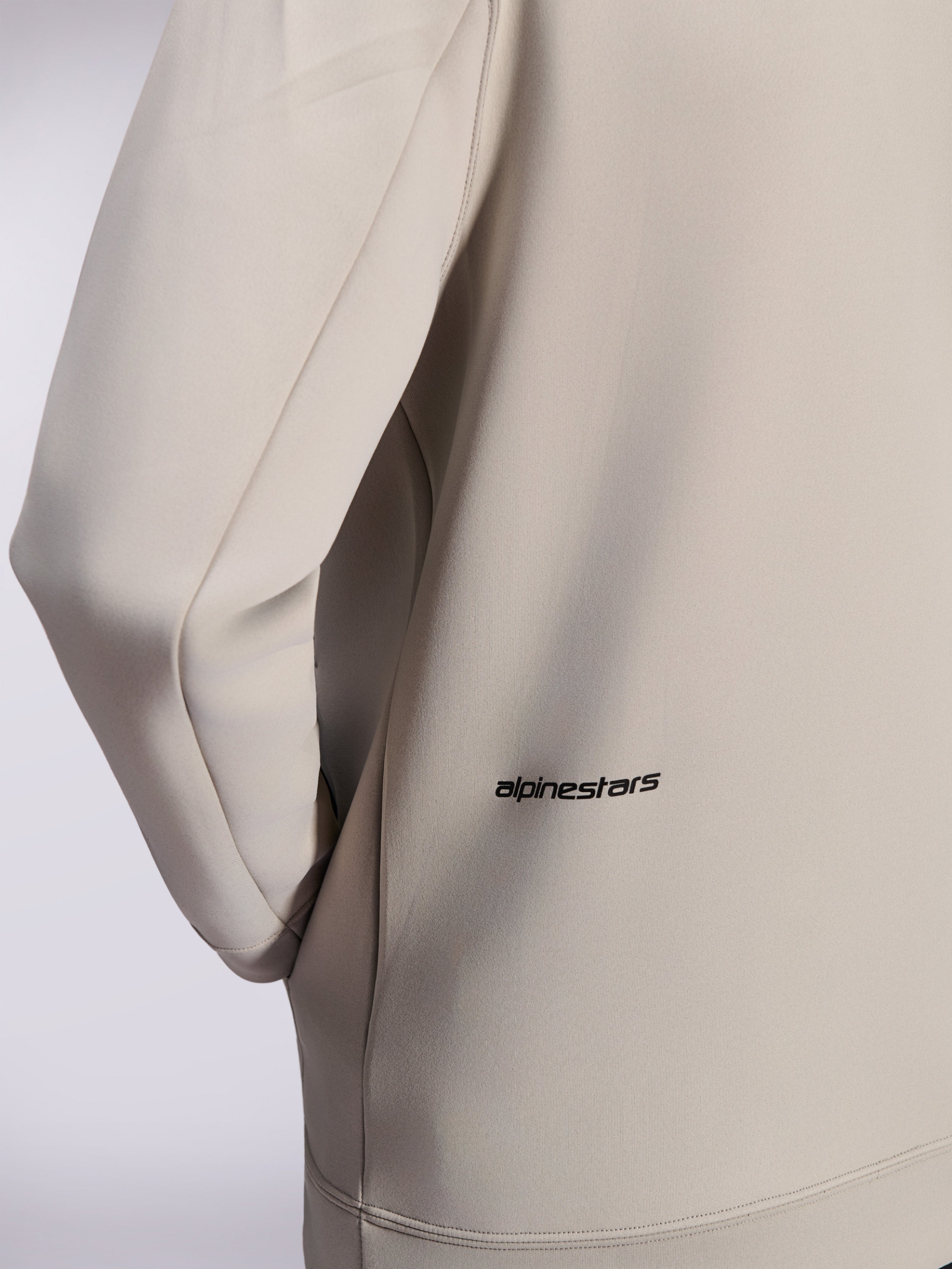 Alpinestars Cypher Hoodie, sudadera con cremallera de forro polar de doble cara, Gris Cemento, primer plano del pequeño logotipo de Alpinestars en la parte inferior de la espalda, detalle del bolsillo en la costura y textura de tejido suave