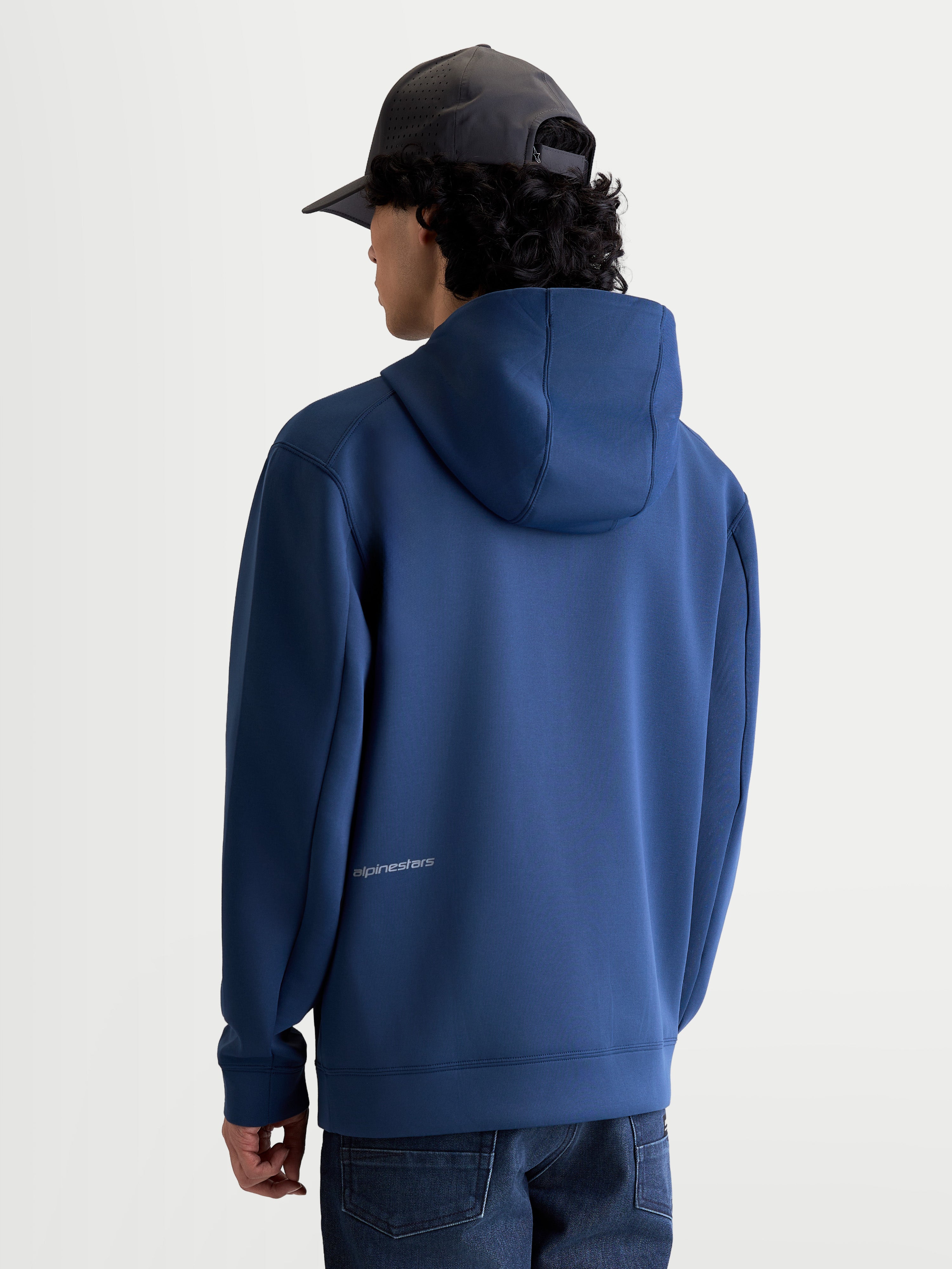 Alpinestars Sudadera con capucha Cypher, forro polar deportivo, azul acero, vista posterior en modelo con capucha de cuello alto y logotipo en la parte inferior de la espalda, tejido de mezcla triple para un estilo casual inspirado en el motorsport.