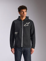 Alpinestars Transverse Hoodie, Black zip-front hooded fleece, featuring white Astars logo and One Goal graphic on the front, worn by a model with dark jeans, casual motorsport-inspired streetwear