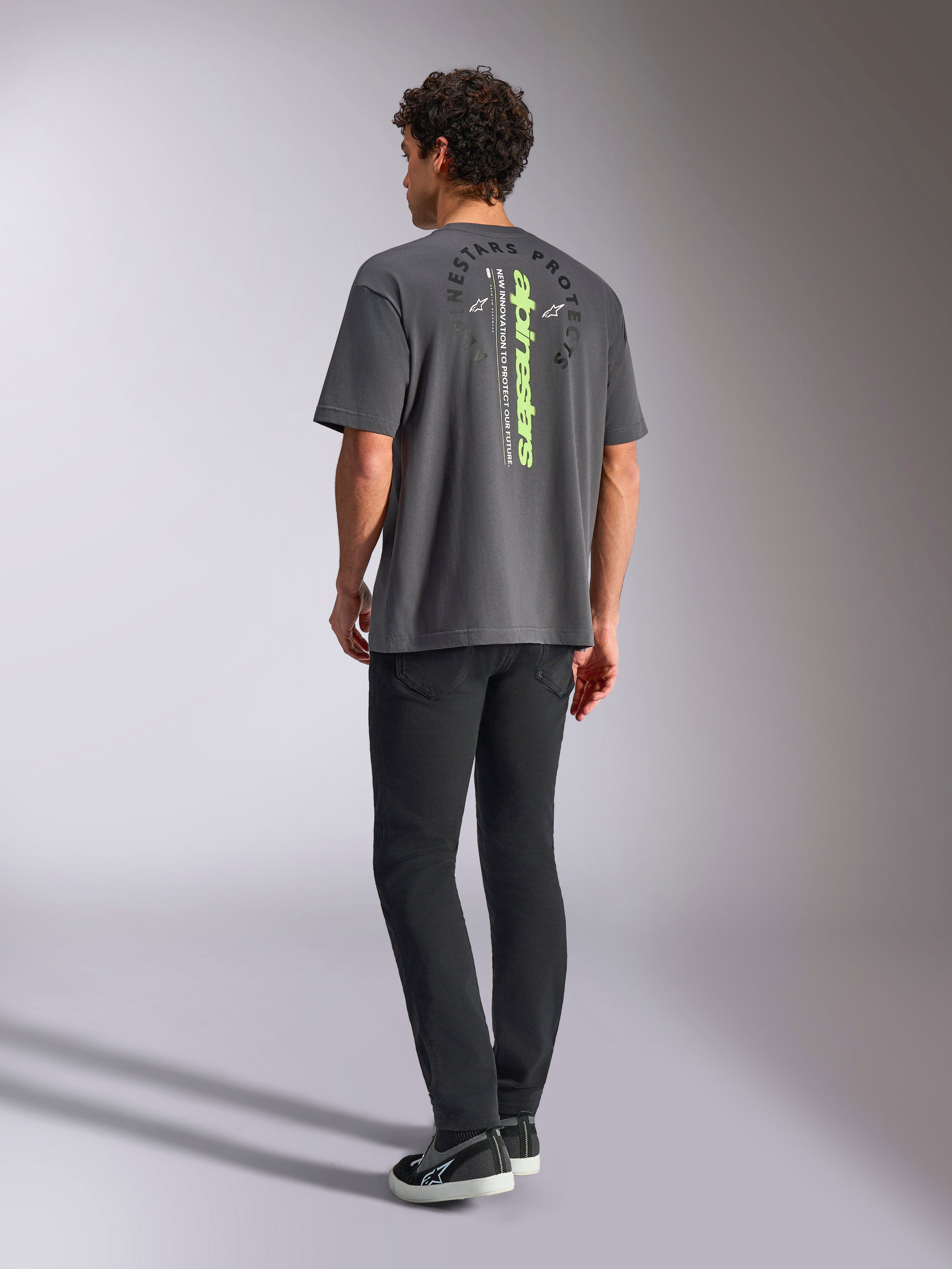 Camiseta Alpinestars Overhang Oversized CSF, camiseta de manga corta, gris carbón, con logotipo vertical en verde lima y gráfico circular Alpinestars Protects en la espalda, ropa urbana casual de estilo motorsport