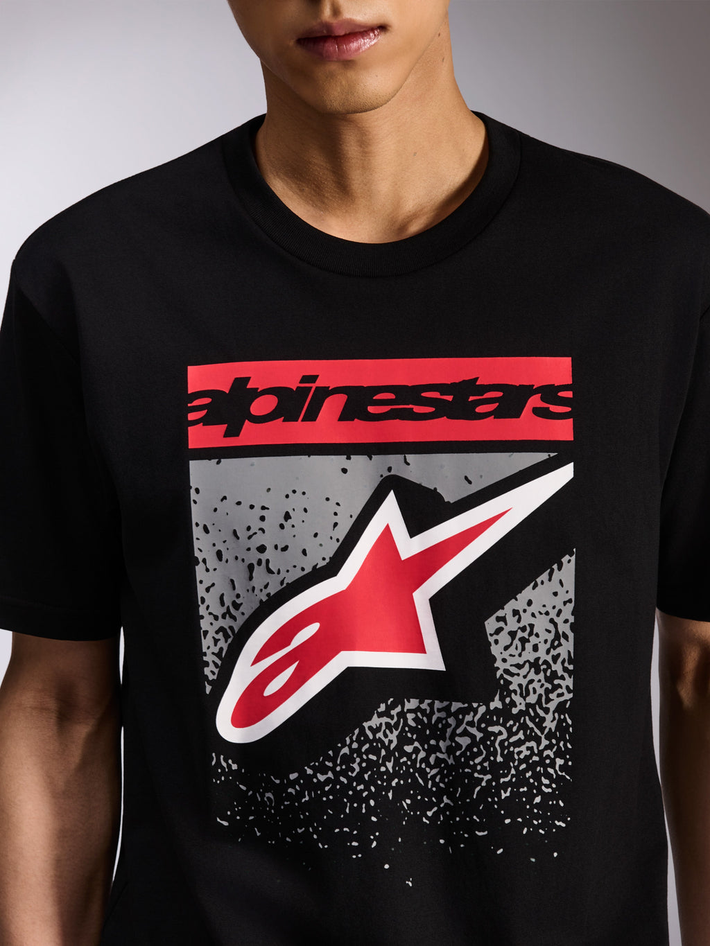 Camiseta Alpinestars Noka CSF, camiseta de manga corta, color negro, gráfico frontal con logotipo Alpinestars en rojo y logo Astars en rojo y blanco sobre un degradado MX gris, ropa casual de estilo motorsport