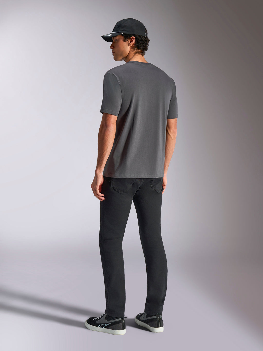 Alpinestars Ellipsoid CSF Tee, camiseta de manga corta, gris carbón, vista trasera, modelo con pantalones negros y gorra de béisbol negra, estilo casual motorsport streetwear