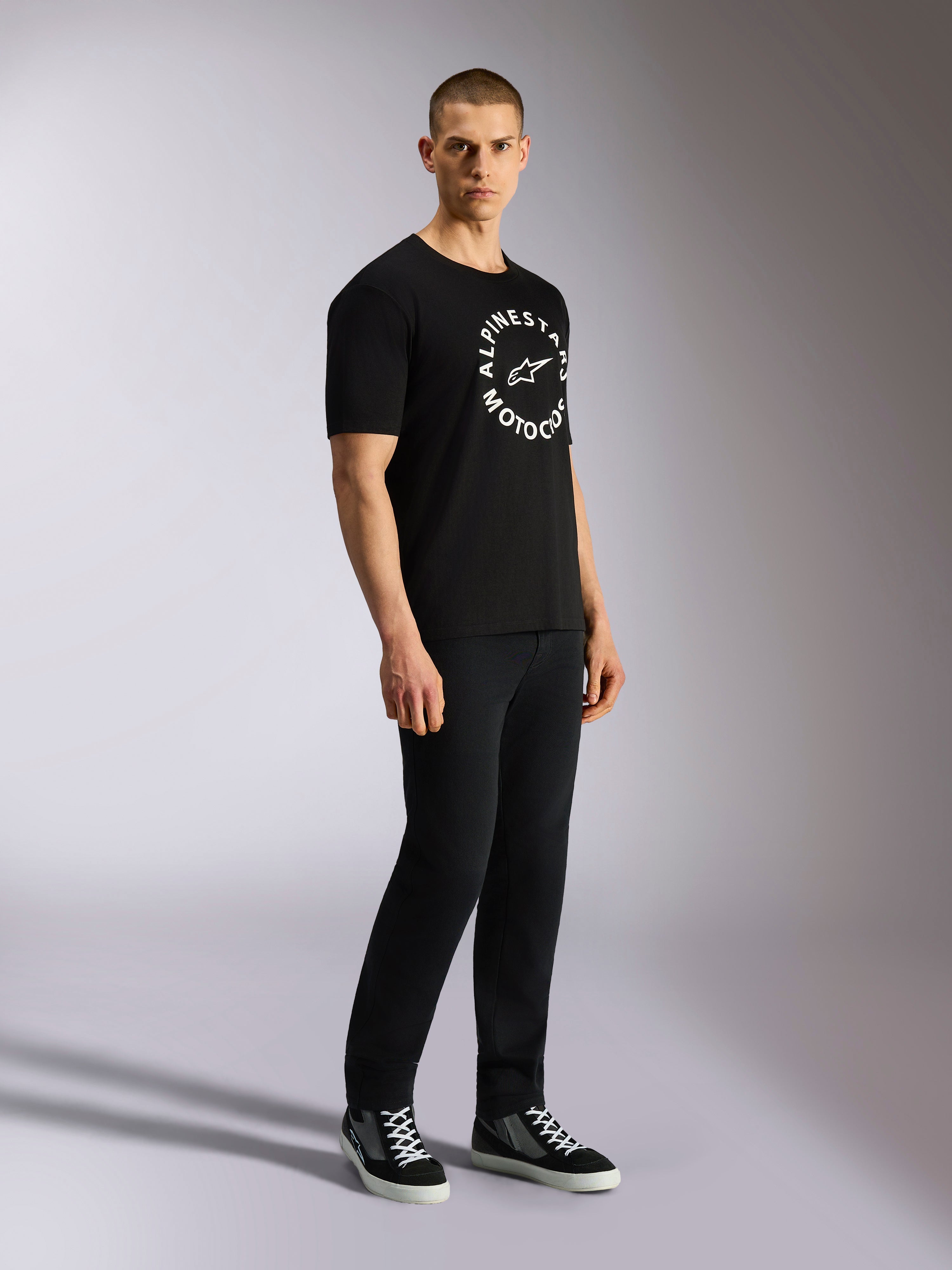 Alpinestars MX CSF Tee, Short Sleeve T-Shirt, Black, White circular Alpinestars Motocross graphic on chest, worn by model with black pants and sneakers, casual motorsport streetwear