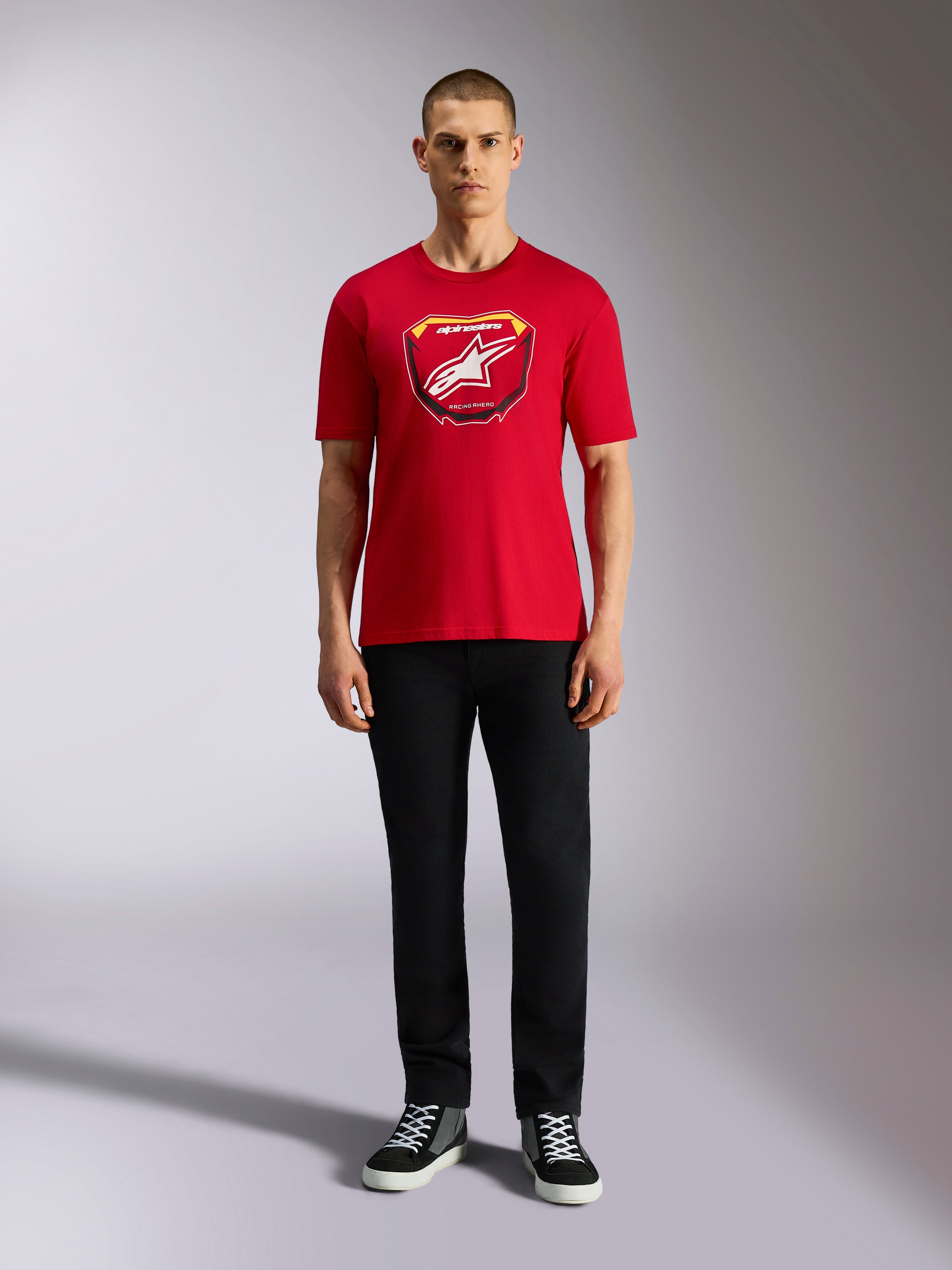 Alpinestars Plate CSF Tee, camiseta de manga corta roja, gráfico frontal de placa MX con logotipo de estrella blanca, combinada con pantalones negros y zapatillas, ropa urbana casual de motorsport