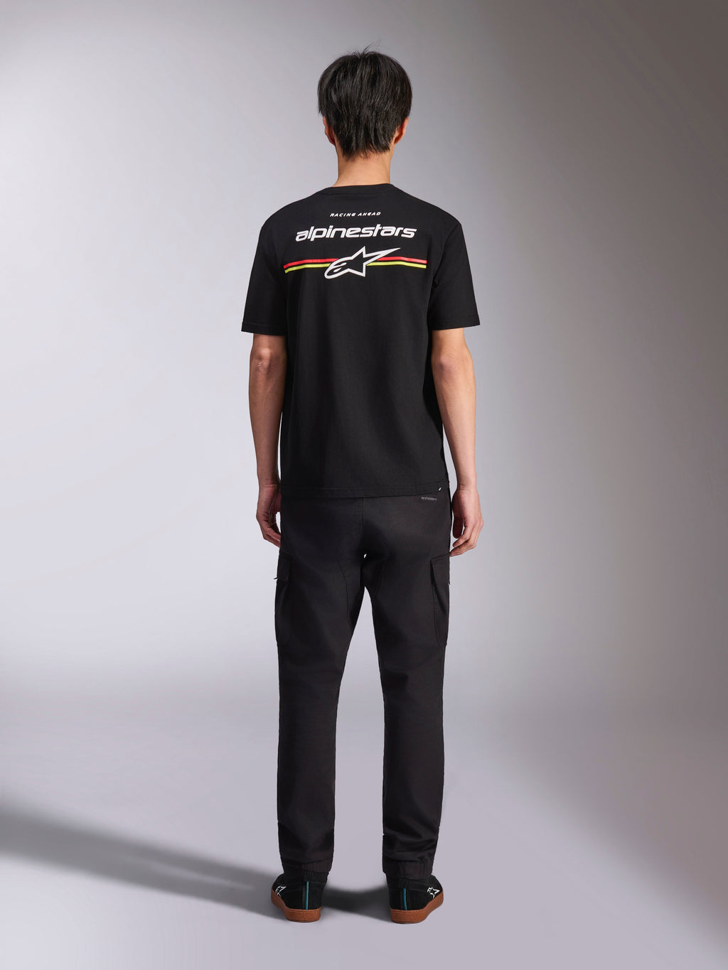 Camiseta Alpinestars Lanes CSF, camiseta de manga corta negra, vista posterior con logotipo de Alpinestars blanco y rayas rojas y amarillas, ropa urbana casual de estilo motorsport