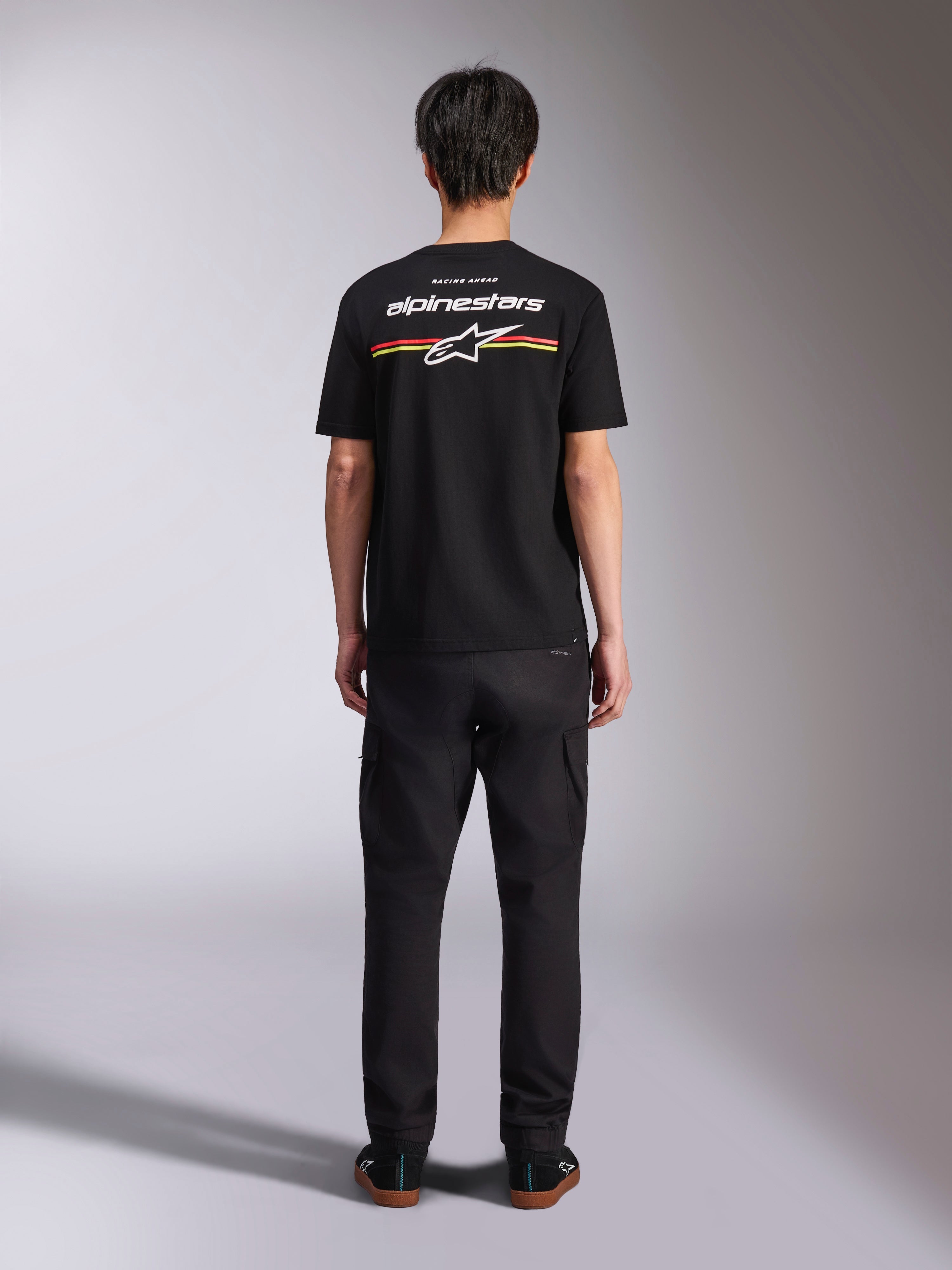 Camiseta Alpinestars Lanes CSF, camiseta de manga corta negra, vista posterior con logotipo de Alpinestars blanco y rayas rojas y amarillas, ropa urbana casual de estilo motorsport