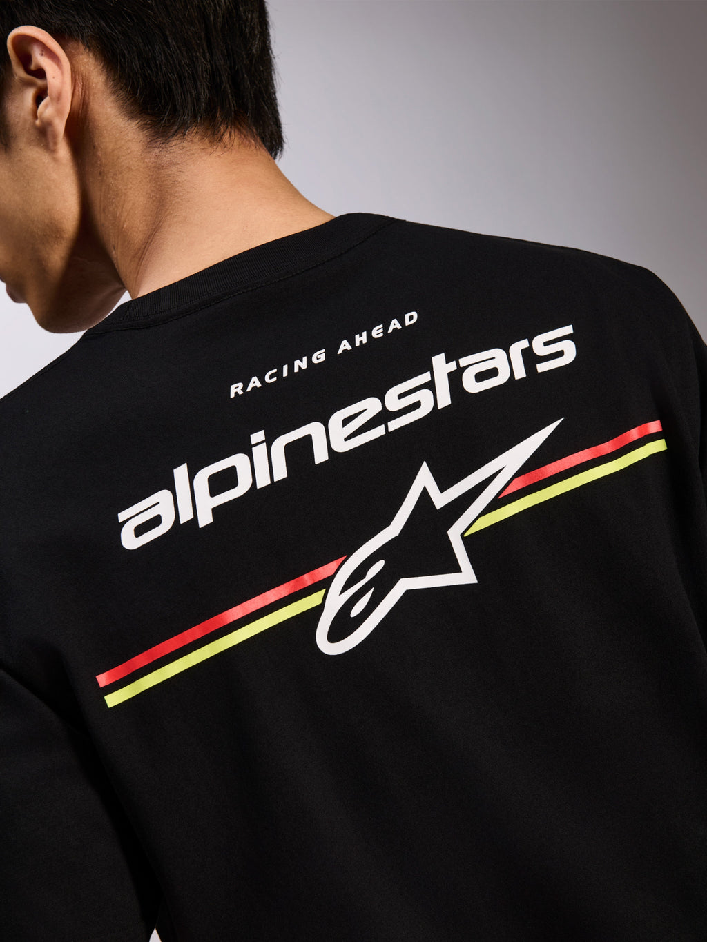 Alpinestars Lanes CSF Tee, camiseta negra de manga corta, gráfico en la espalda con logotipos de Alpinestars y Astars en blanco sobre franjas rojas y amarillas, ropa urbana casual de motor
