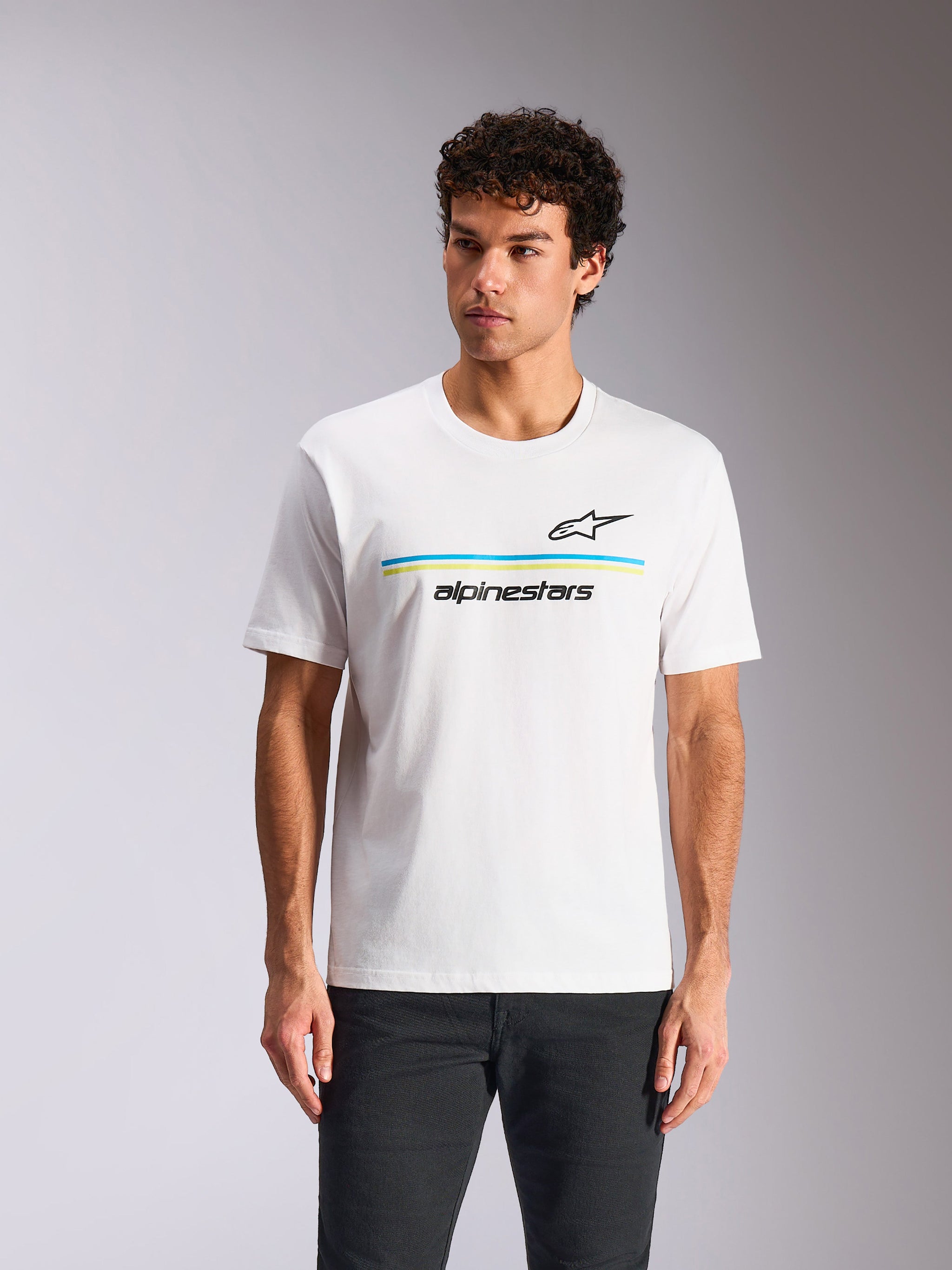 Camiseta Alpinestars Lanes CSF, camiseta de manga corta, blanca, con el logotipo Astars negro sobre franjas horizontales azules y verde lima y el texto 'alpinestars', lucida por un modelo, estilo casual motorsport streetwear