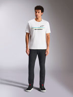 Alpinestars Lanes CSF Tee, camiseta de manga corta, blanca, gráfico de logotipo con franjas azules y amarillas, usada por un modelo con pantalones negros y zapatillas, ropa urbana casual de automovilismo