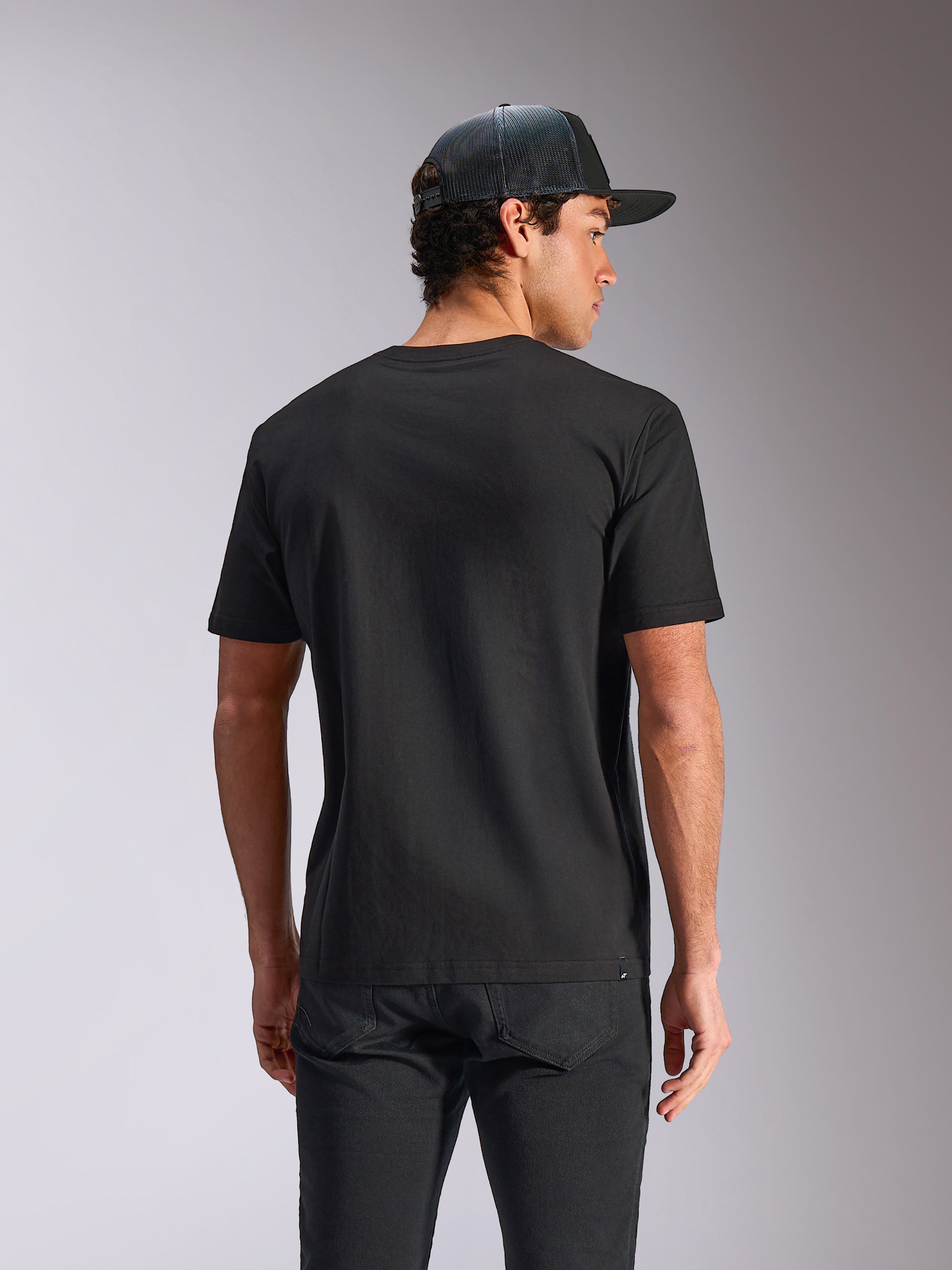 Alpinestars Verdure Camo CSF Tee, camiseta de manga corta, negra, vista posterior, usada con una gorra de rejilla y pantalones negros, estilo casual motorsport streetwear