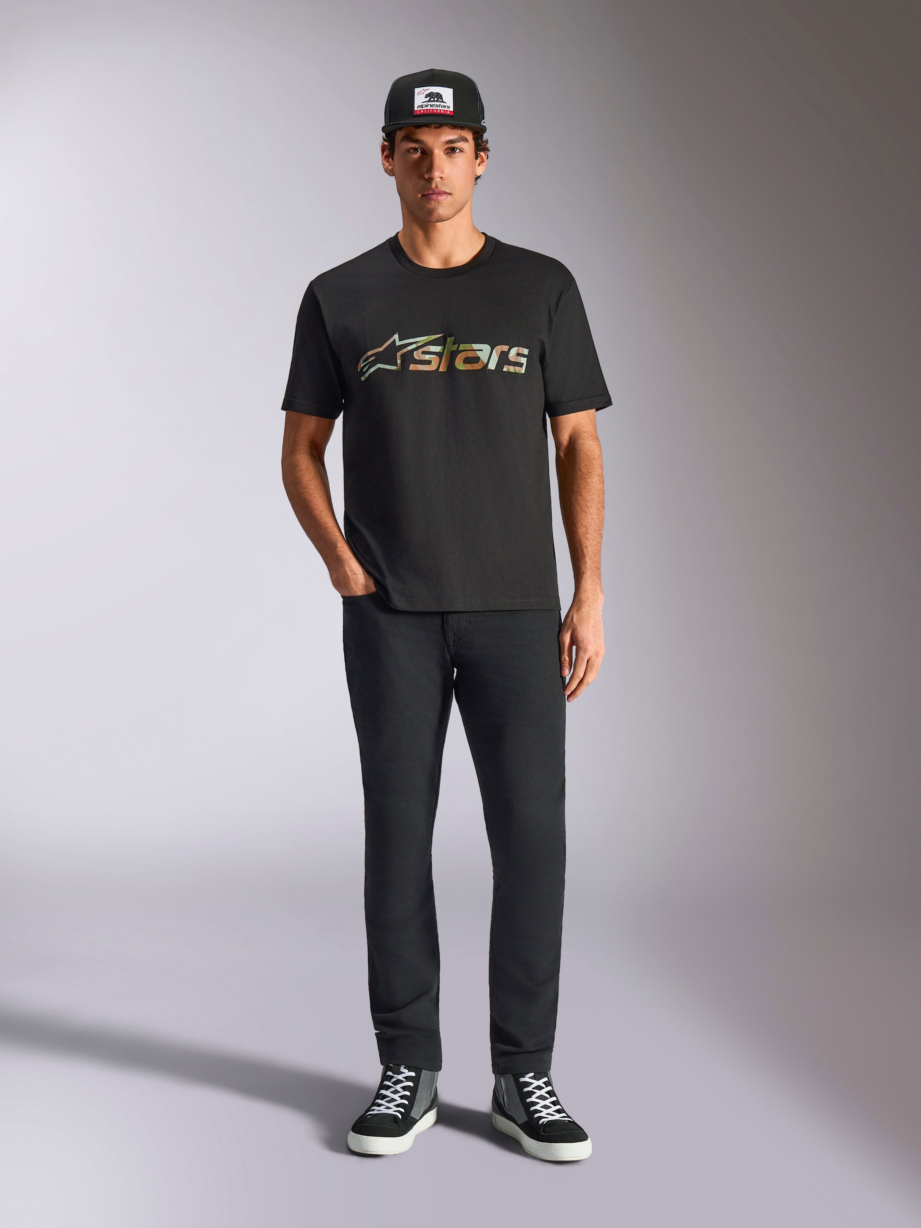 Alpinestars Verdure Camo CSF Tee, camiseta de manga corta, negra, con el logotipo de Astars en patrón de camuflaje en el pecho, usada por un modelo con gorra negra y pantalones negros, ropa urbana casual de motociclismo