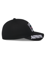 Alpinestars Surpass Hat, Black, side profile view, curved bill with white 'ALPINESTARS PROTECTS' embroidery, structured crown with front logo patch, casual motorsport-inspired headwear