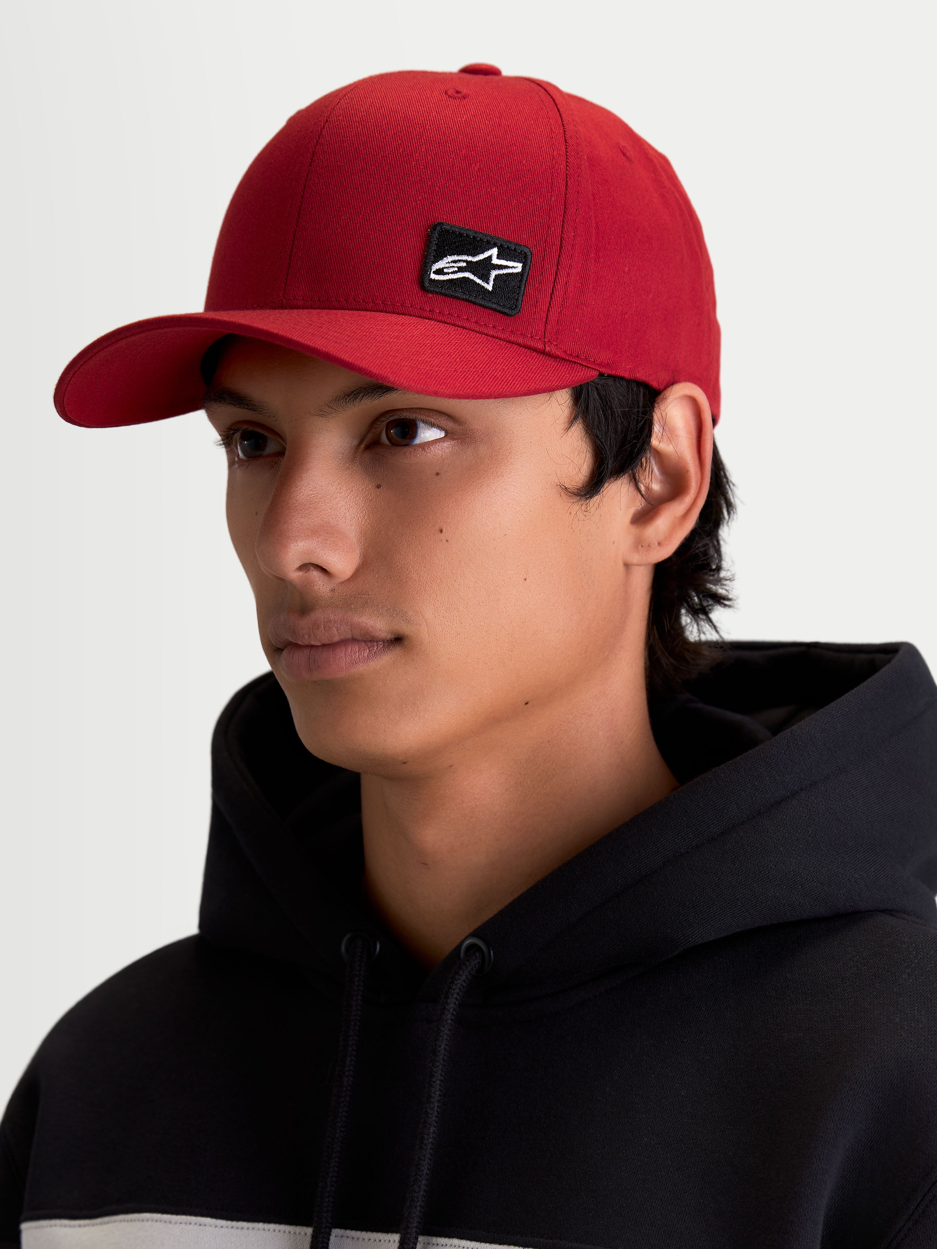 Alpinestars Gorra Pivot, gorra de estilo de vida sportswear para hombre y mujer, roja oscura, con visera curva, corona estructurada y parche bordado con logotipo Astars negro, mostrada en modelo