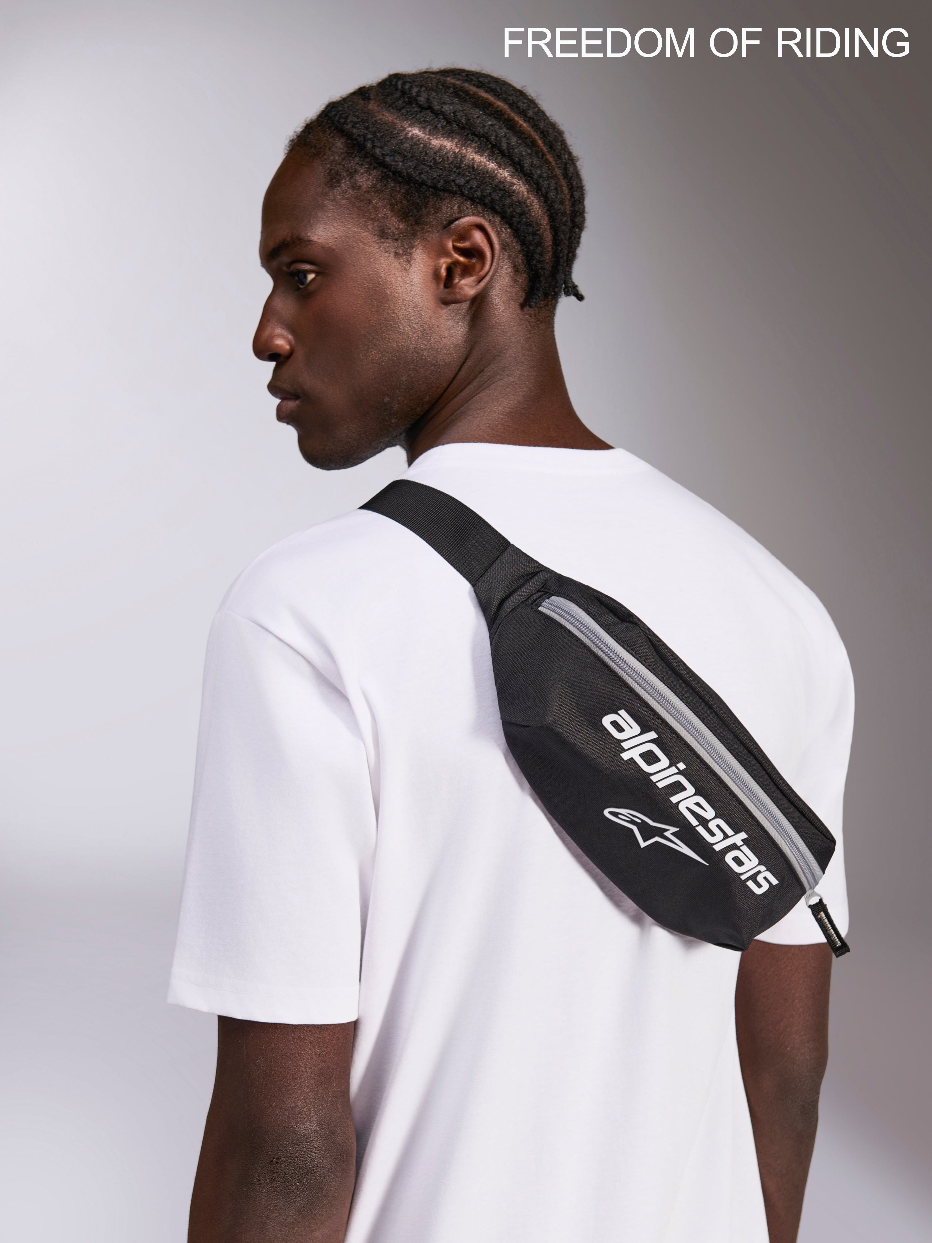 Alpinestars Only Linear Hip Bag, Sportswear Crossbody Waist Pack, Black and White, 2L Capacity, Durable 600D Polyester, worn by a model over a white t-shirt for urban commuting and everyday use.