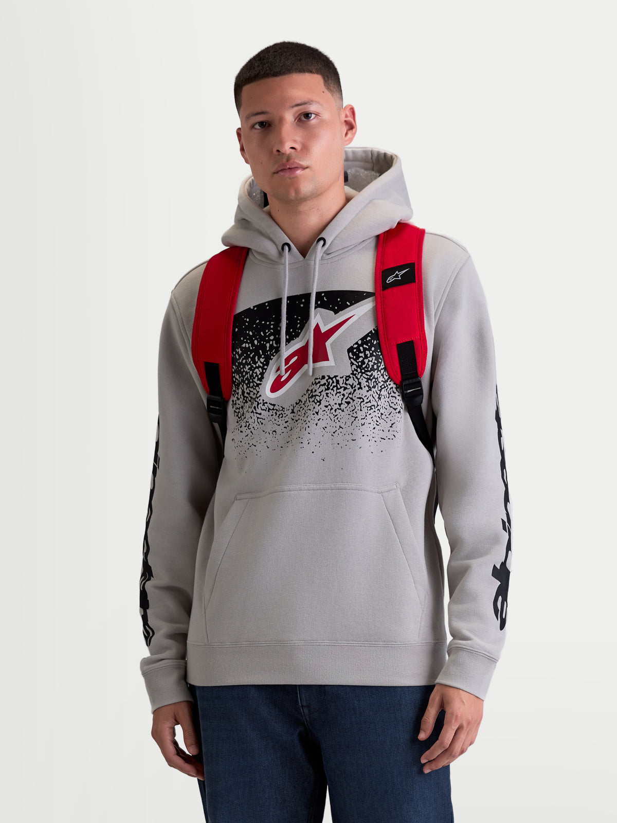 Alpinestars Mochila GFX Boss, mochila urbana de 20L para hombre y mujer, roja y negra, poliéster 600D duradero, vista frontal en modelo con correas de hombro ajustables de malla de aire y logotipo de silicona en relieve