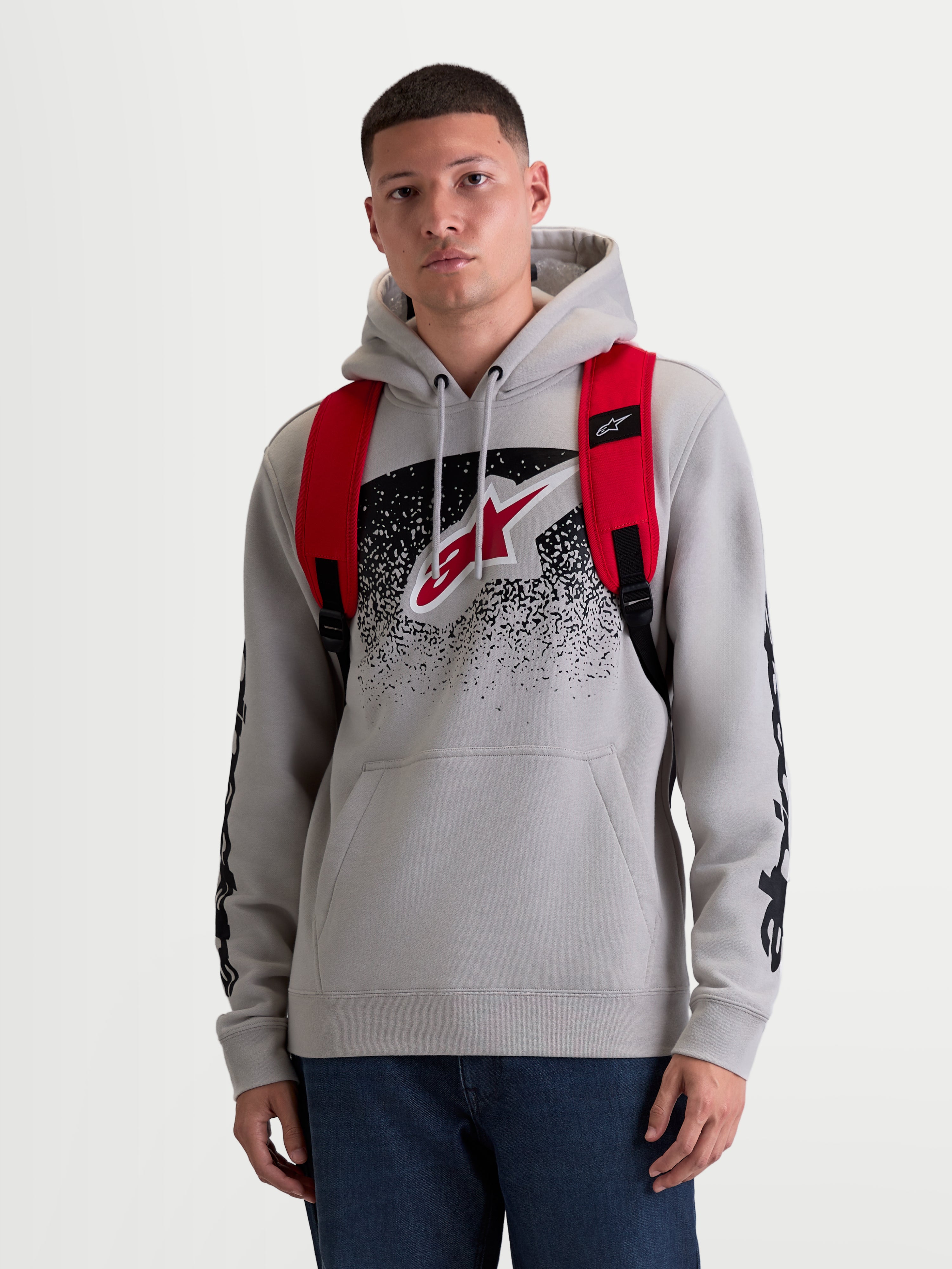 Alpinestars Mochila GFX Boss, mochila urbana de 20L para hombre y mujer, roja y negra, poliéster 600D duradero, vista frontal en modelo con correas de hombro ajustables de malla de aire y logotipo de silicona en relieve