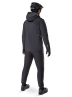 Chaqueta Impermeable Alpinestars A-Dura Elite, color negro, vista trasera que muestra la capucha compatible con el casco y el dobladillo trasero más largo, combinada con pantalones de MTB, guantes y casco negros a juego para una protección completa en senderos bajo cualquier condición climática.
