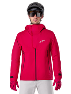 Alpinestars A-Dura Elite Waterproof Jacket, chaqueta de lluvia para MTB, rojo flúor, cuello alto con logotipo de Alpinestars en blanco, detalles de cremalleras negras, usada con guantes a juego y casco de ciclismo negro, equipamiento técnico impermeable