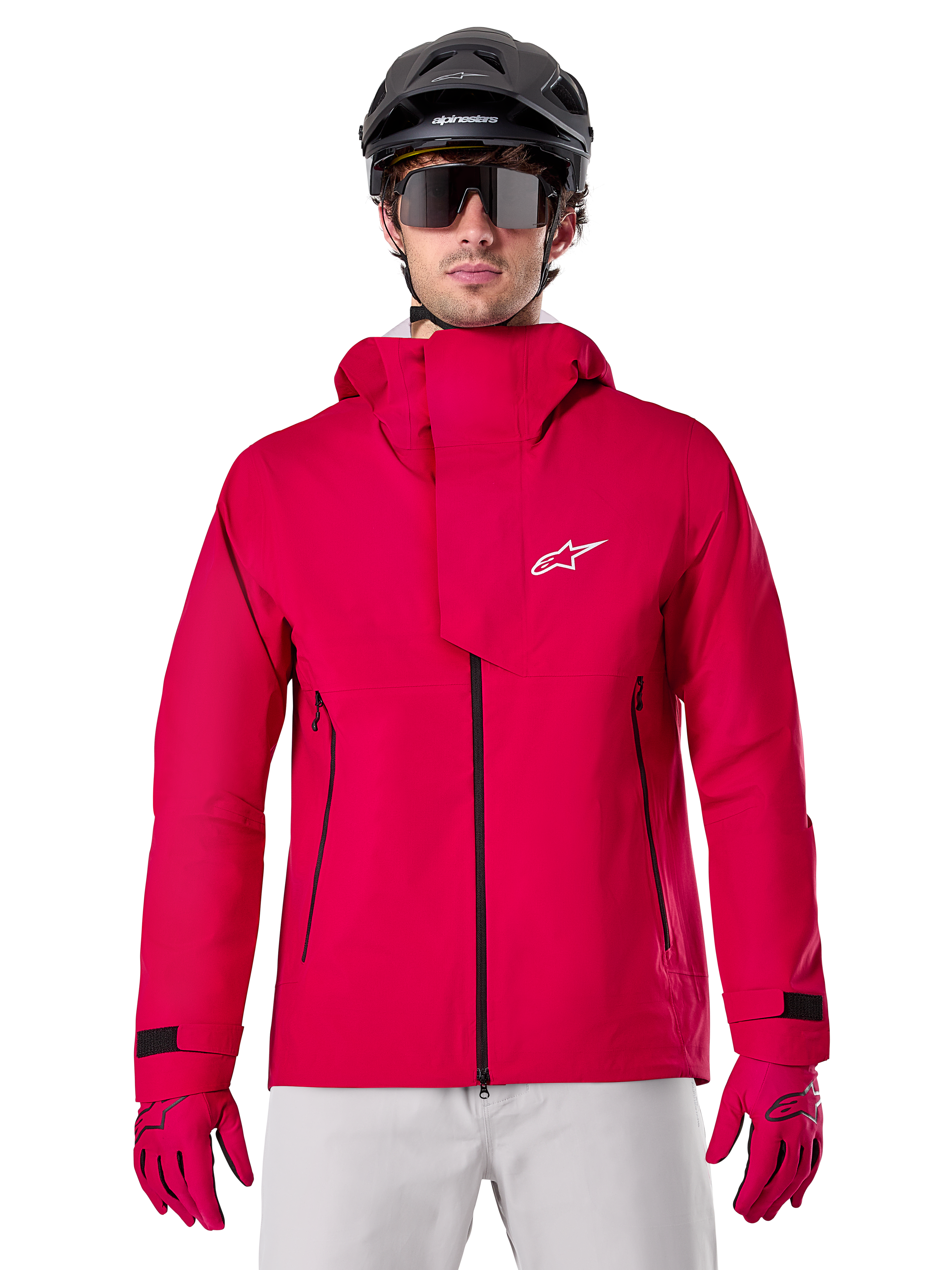 Alpinestars A-Dura Elite Waterproof Jacket, chaqueta de lluvia para MTB, rojo flúor, cuello alto con logotipo de Alpinestars en blanco, detalles de cremalleras negras, usada con guantes a juego y casco de ciclismo negro, equipamiento técnico impermeable
