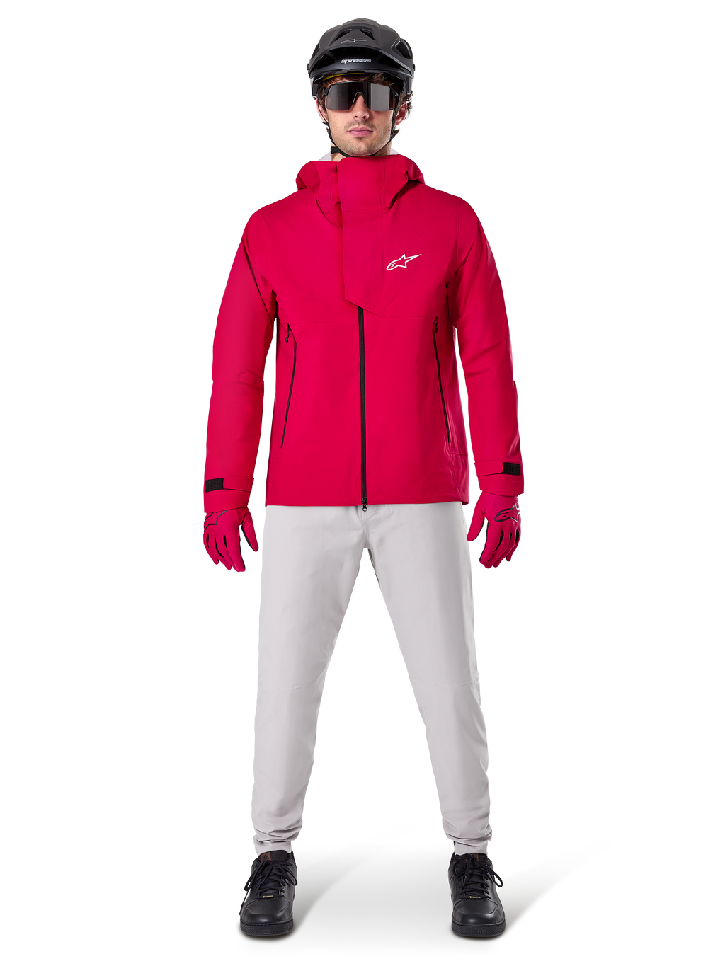 Chaqueta impermeable Alpinestars A-Dura Elite, Rojo Fluo, chaqueta técnica de montaña usada con un casco negro de MTB, gafas de sol, guantes rojos a juego y pantalones gris claro, vista de cuerpo completo del equipamiento de ciclismo para todo tipo de clima