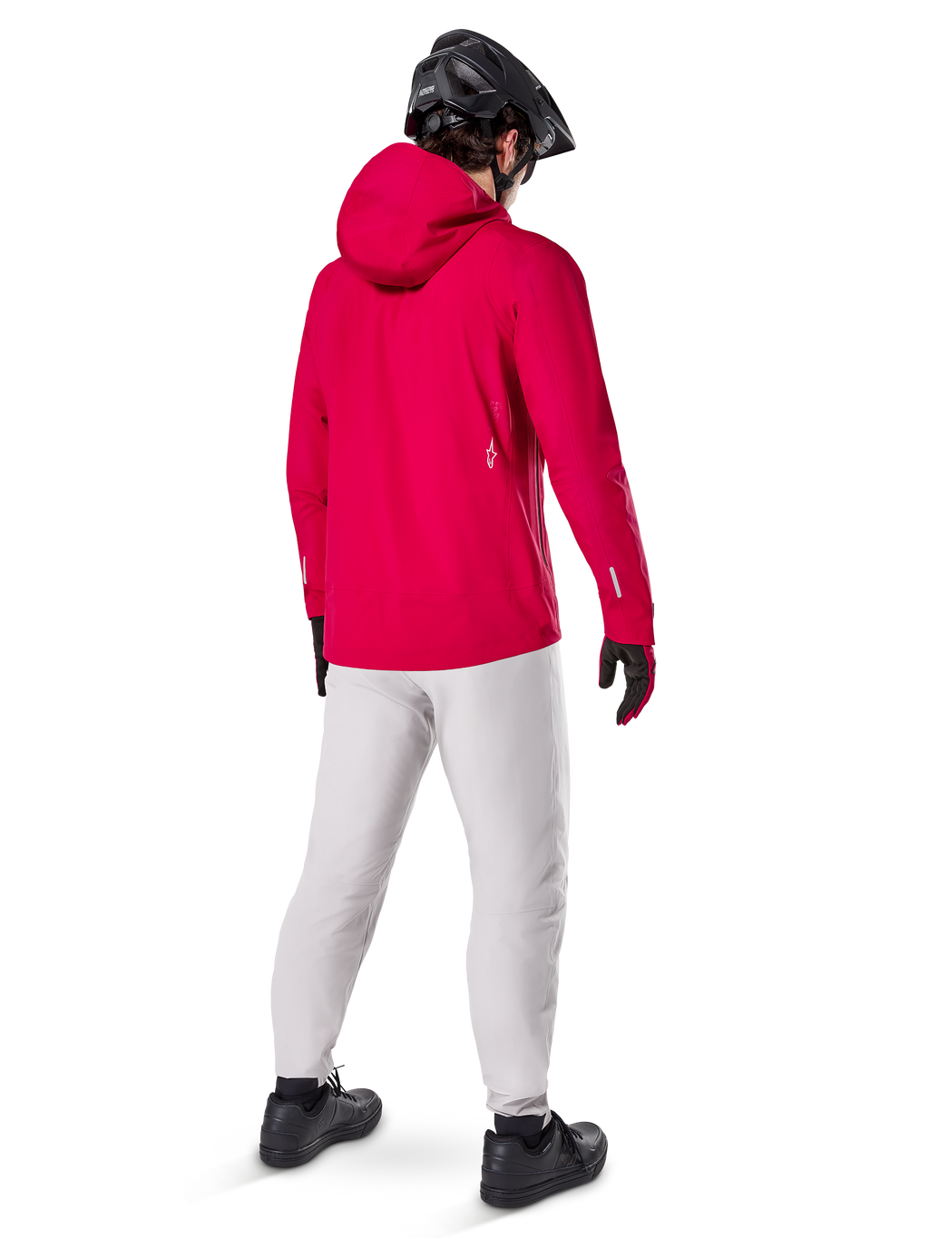 Alpinestars A-Dura Elite, chaqueta impermeable, Rojo Fluo, vista trasera de tres cuartos, combinada con pantalones gris claro y casco de MTB negro, cuenta con capucha y detalles reflectantes, chaqueta de lluvia de alto rendimiento para ciclismo de montaña