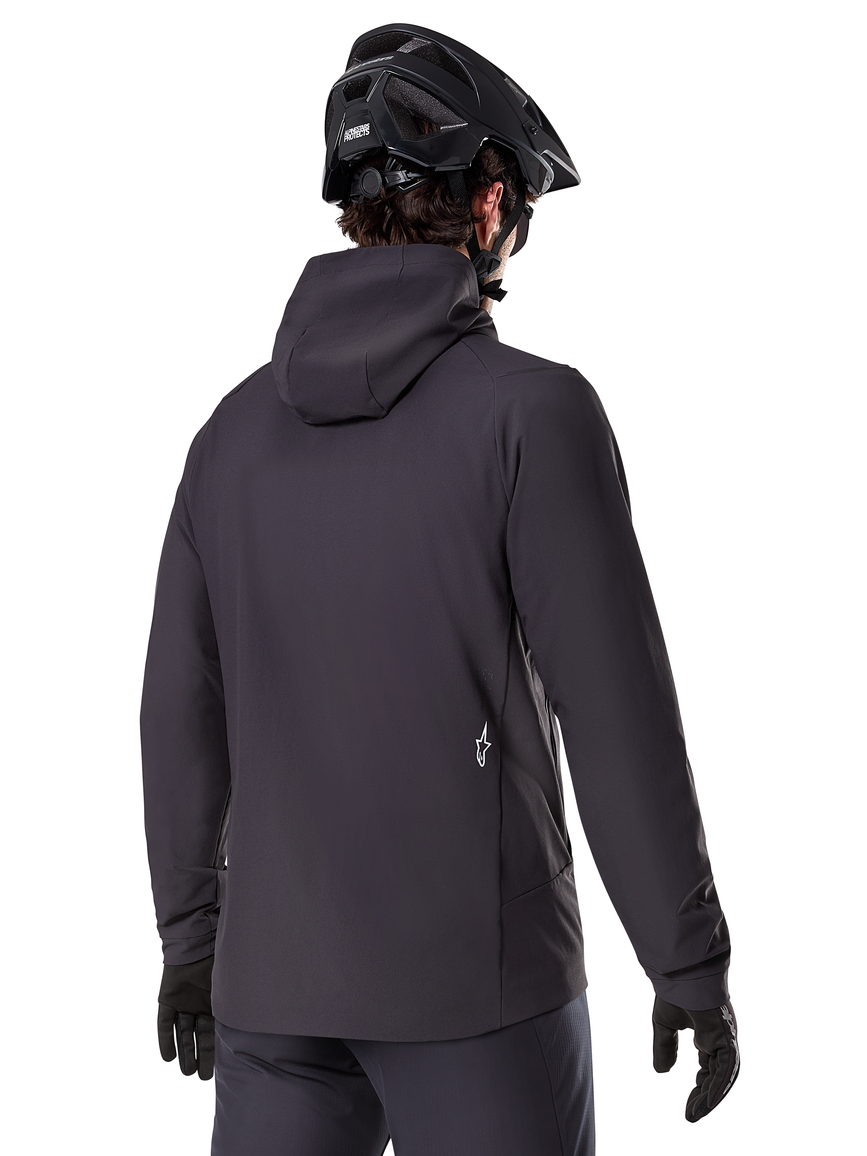 Alpinestars A-Dura Thermal Jacket, negra, vista trasera, usada con un casco de bicicleta de montaña negro y guantes, cuenta con un pequeño logo blanco de Astars en la parte baja de la espalda, chaqueta de ciclismo ligera con aislamiento térmico