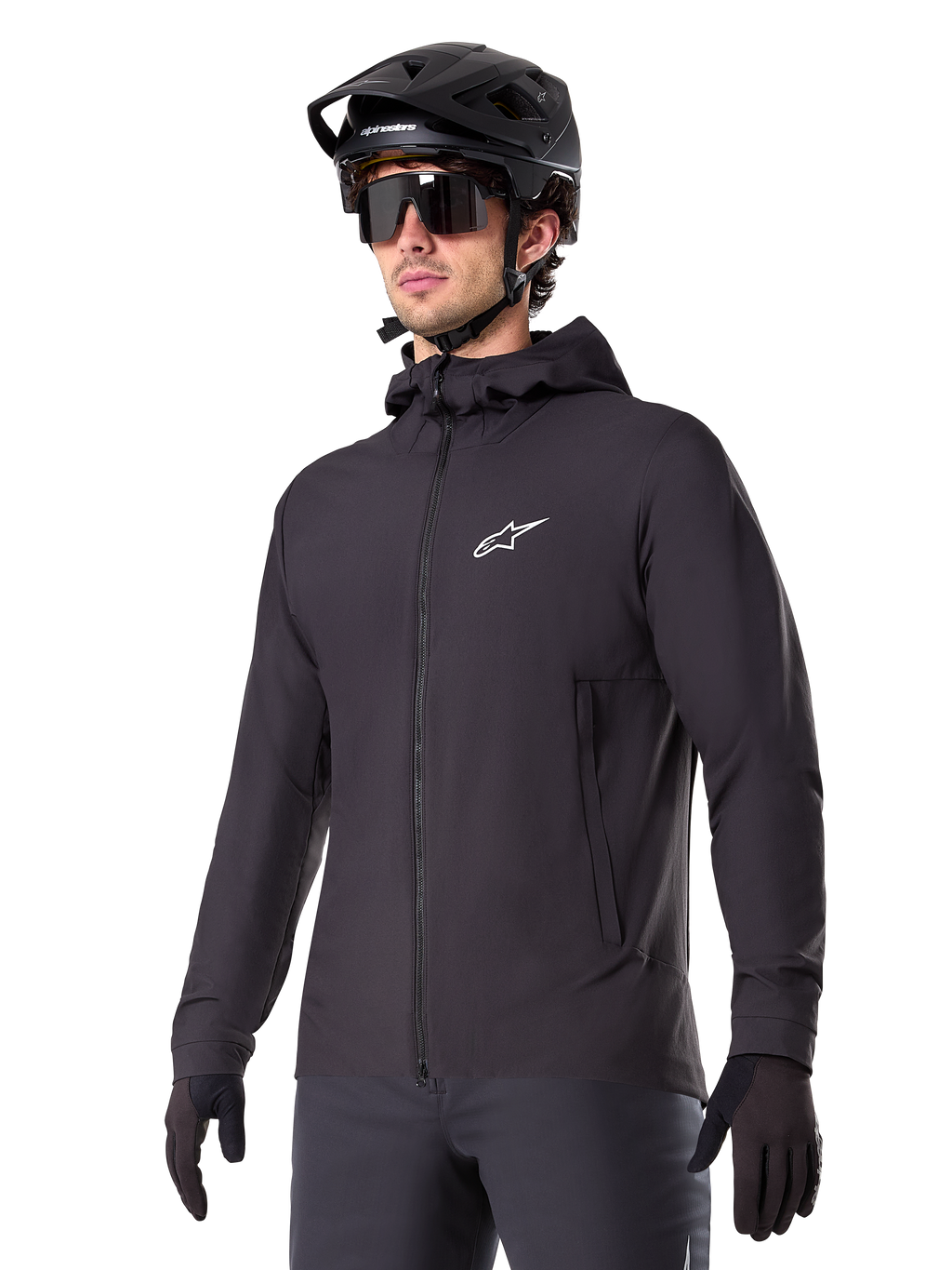 Alpinestars A-Dura Thermal Jacket, chaqueta de ciclismo negra, diseño con capucha y cremallera frontal, logotipo de estrella blanca en el pecho, usada con casco de bicicleta de montaña y guantes negros, equipamiento deportivo de alto rendimiento para rutas en climas fríos
