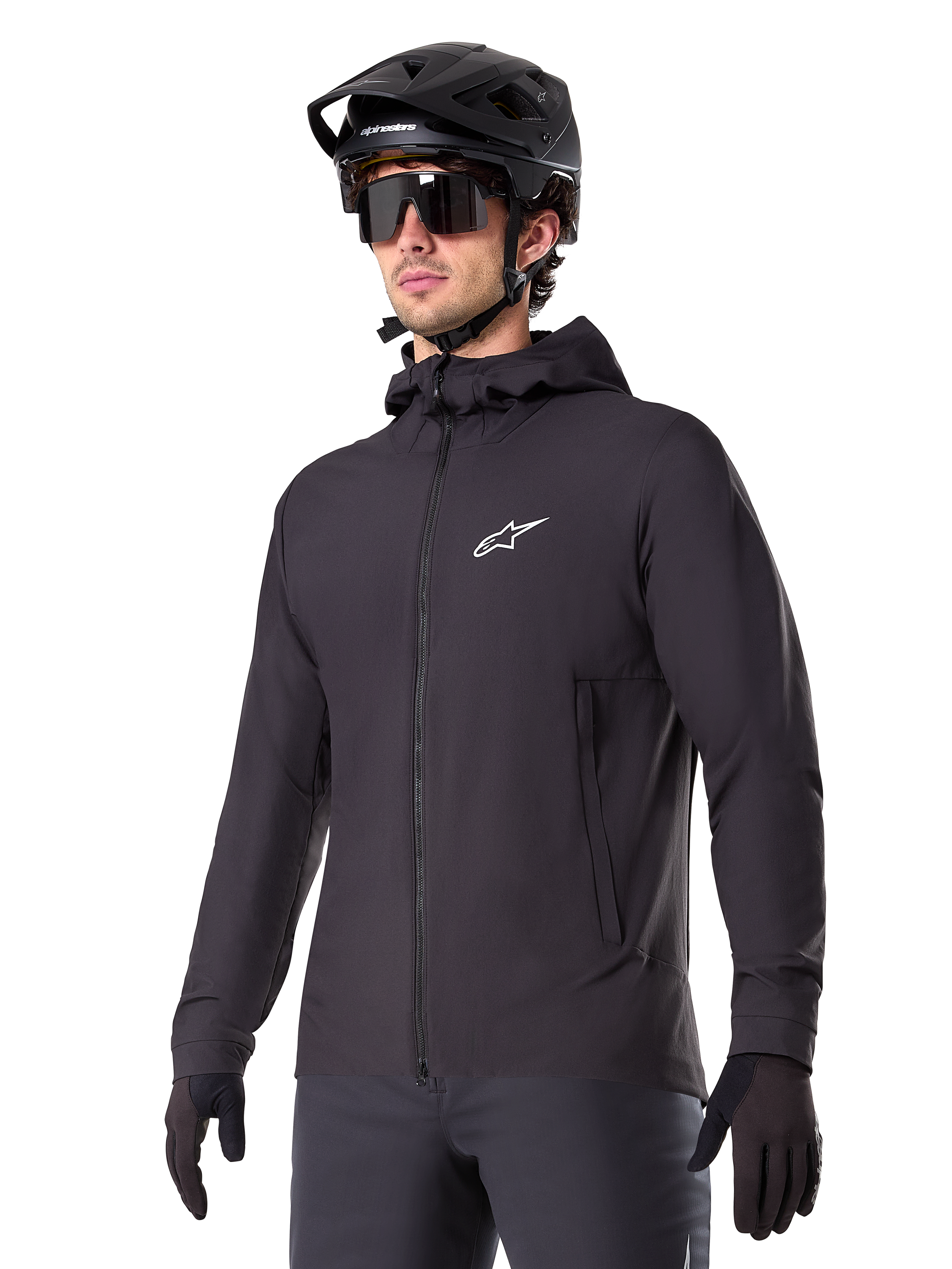 Alpinestars A-Dura Thermal Jacket, chaqueta de ciclismo negra, diseño con capucha y cremallera frontal, logotipo de estrella blanca en el pecho, usada con casco de bicicleta de montaña y guantes negros, equipamiento deportivo de alto rendimiento para rutas en climas fríos