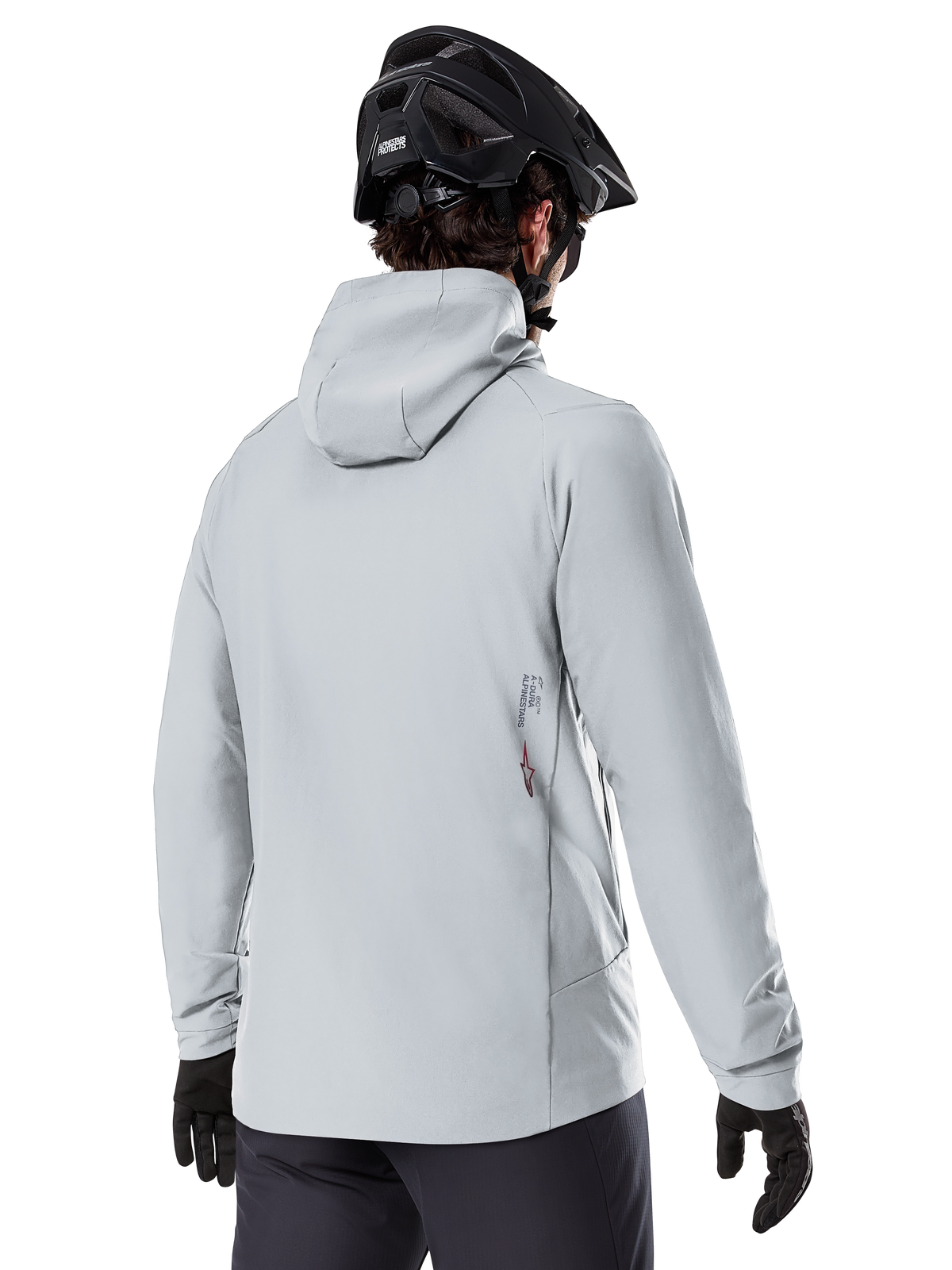 Chaqueta térmica Alpinestars A-Dura, Gris Titanium, vista posterior de un ciclista con la chaqueta aislante con capucha, combinada con un casco de MTB negro y guantes negros, con un pequeño logotipo de Alpinestars en la parte inferior de la espalda, diseñada para ciclismo de montaña en climas fríos.