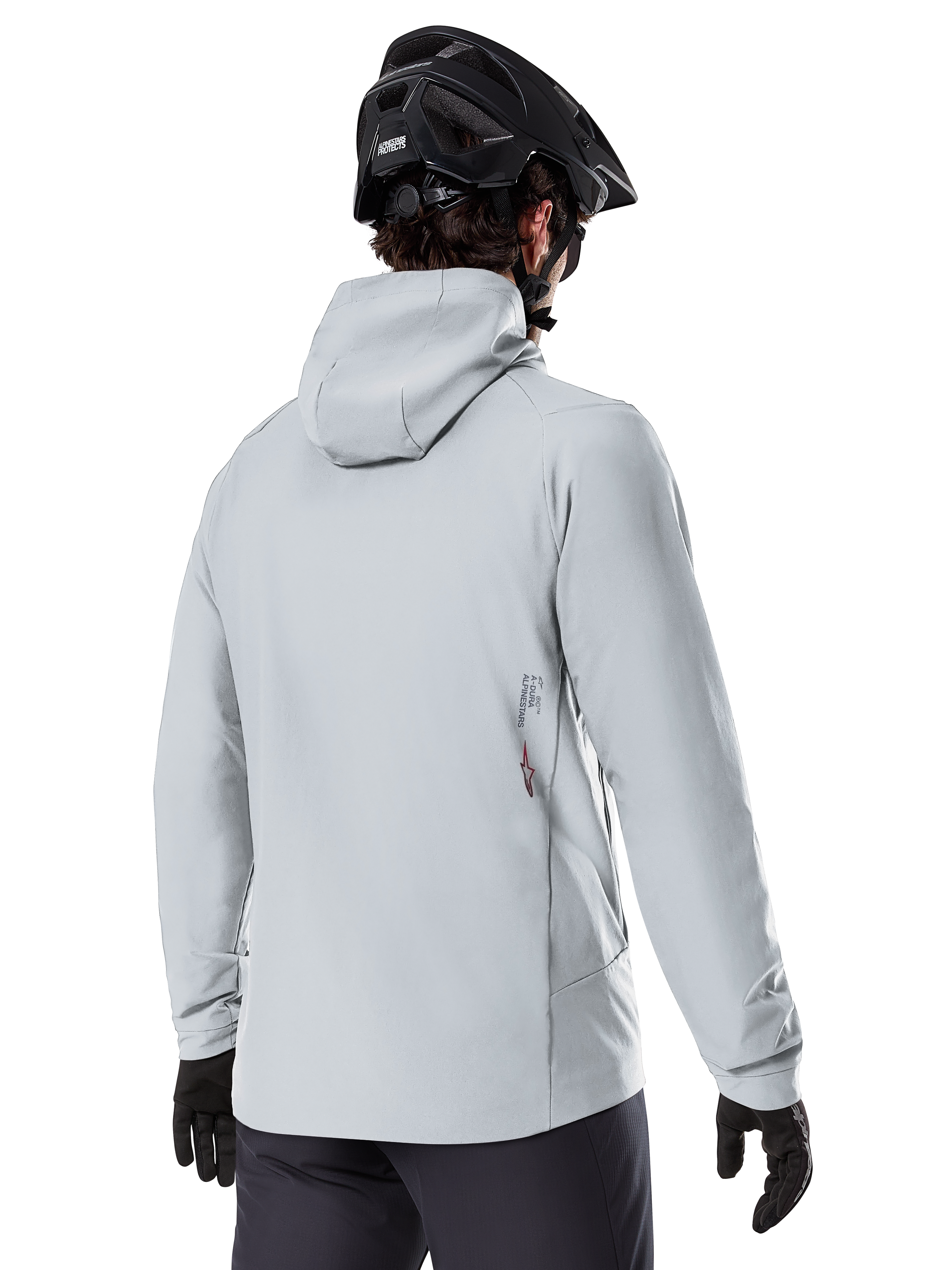 Chaqueta térmica Alpinestars A-Dura, Gris Titanium, vista posterior de un ciclista con la chaqueta aislante con capucha, combinada con un casco de MTB negro y guantes negros, con un pequeño logotipo de Alpinestars en la parte inferior de la espalda, diseñada para ciclismo de montaña en climas fríos.