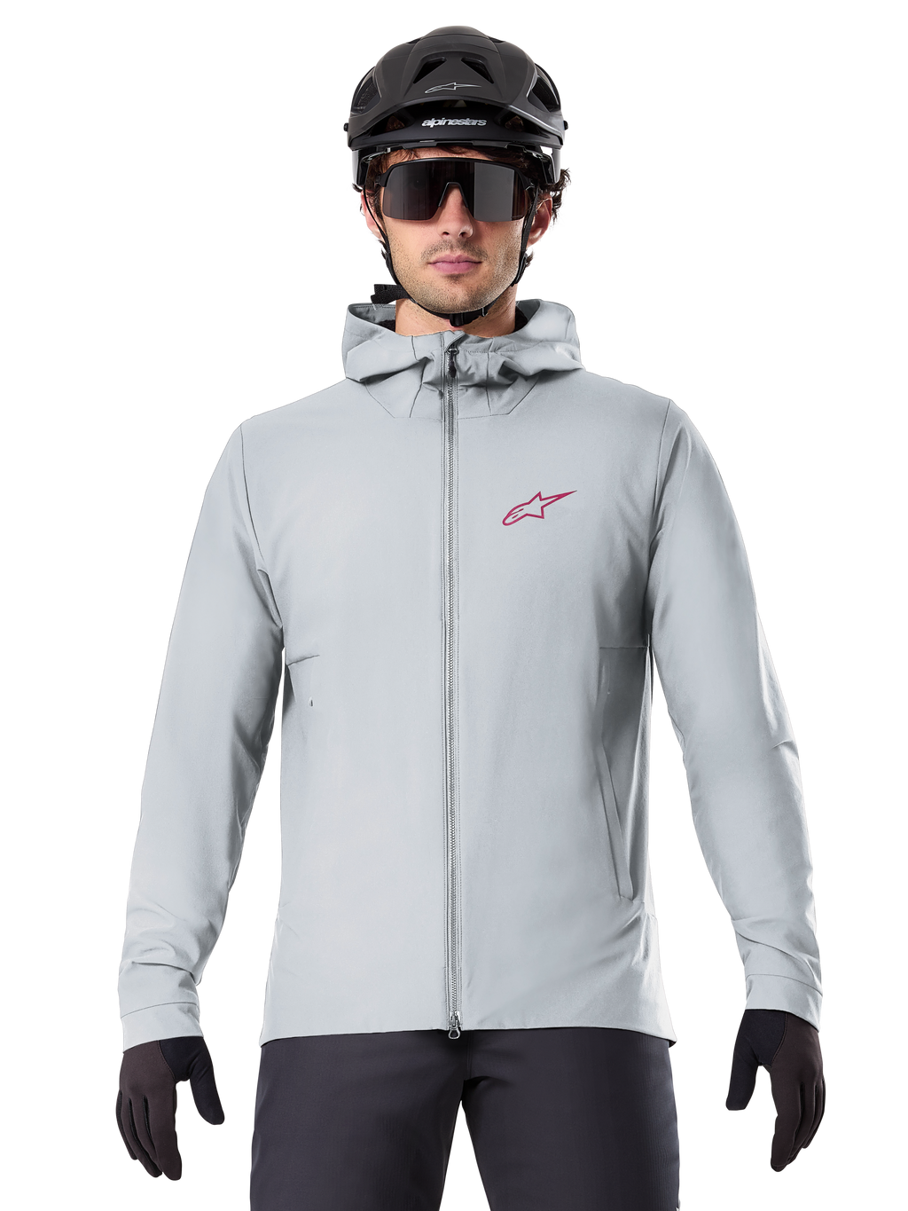 Chaqueta térmica Alpinestars A-Dura en color Titanium, chaqueta de ciclismo con capucha en gris claro con un logotipo de estrella roja en el pecho, usada por un ciclista con casco de MTB negro, gafas de sol y guantes, equipamiento aislante para ciclismo de montaña