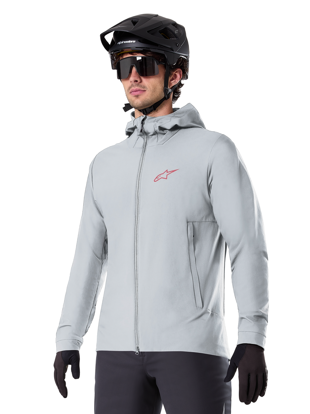 Alpinestars A-Dura Thermal Jacket, chaqueta de ciclismo gris claro con aislamiento, diseño con capucha y un pequeño logotipo rojo, usada con casco y guantes negros, ropa técnica de mountain bike para climas fríos