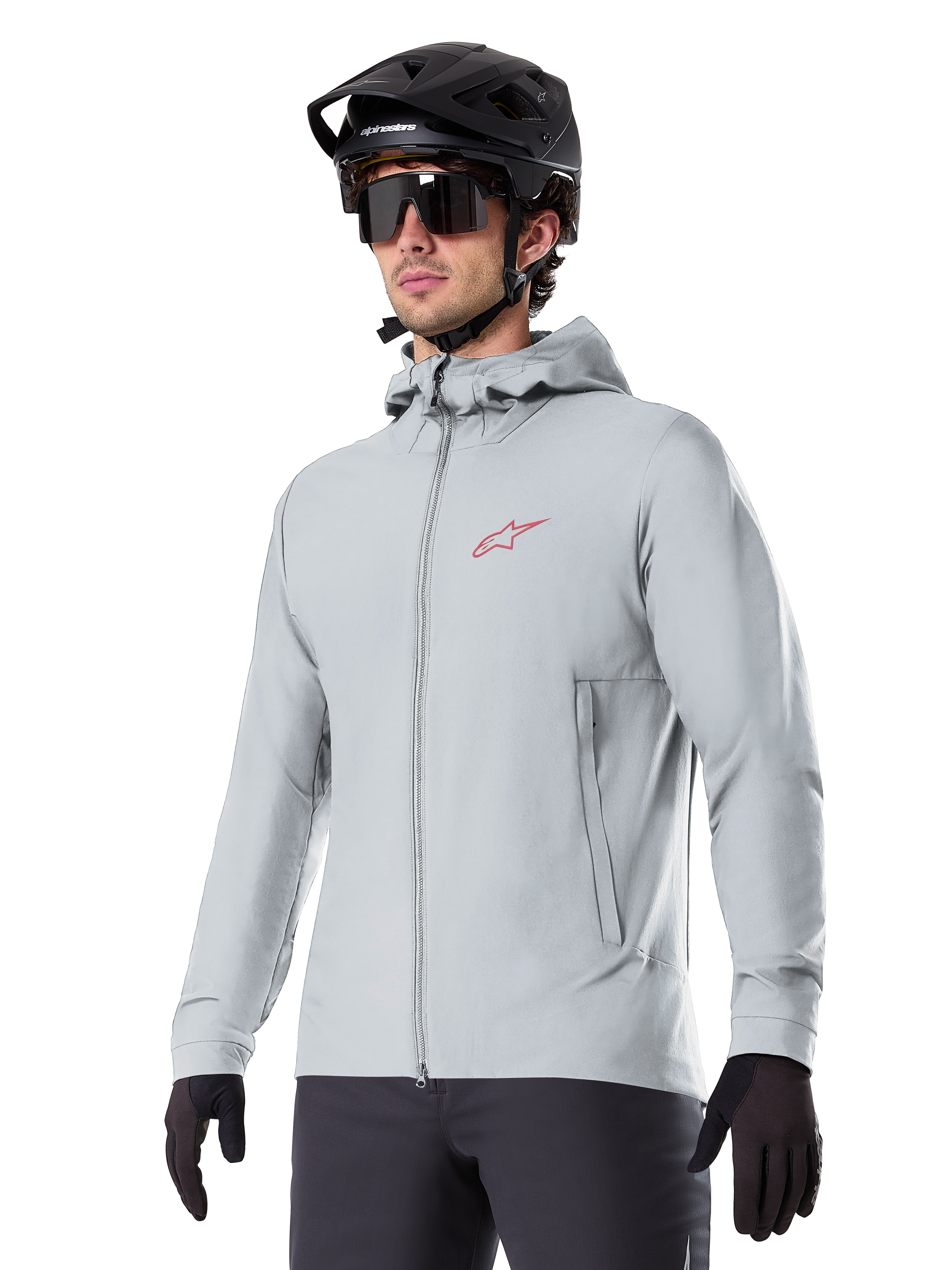 Alpinestars A-Dura Thermal Jacket, chaqueta de ciclismo gris claro con aislamiento, diseño con capucha y un pequeño logotipo rojo, usada con casco y guantes negros, ropa técnica de mountain bike para climas fríos