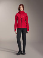 Chaqueta impermeable Alpinestars Stella A-Dura Elite, chaqueta de MTB para mujer, rojo fluo, combinada con pantalones y calzado negros, con capucha de cuello alto y logotipo blanco de Alpinestars, equipamiento técnico de ciclismo de montaña