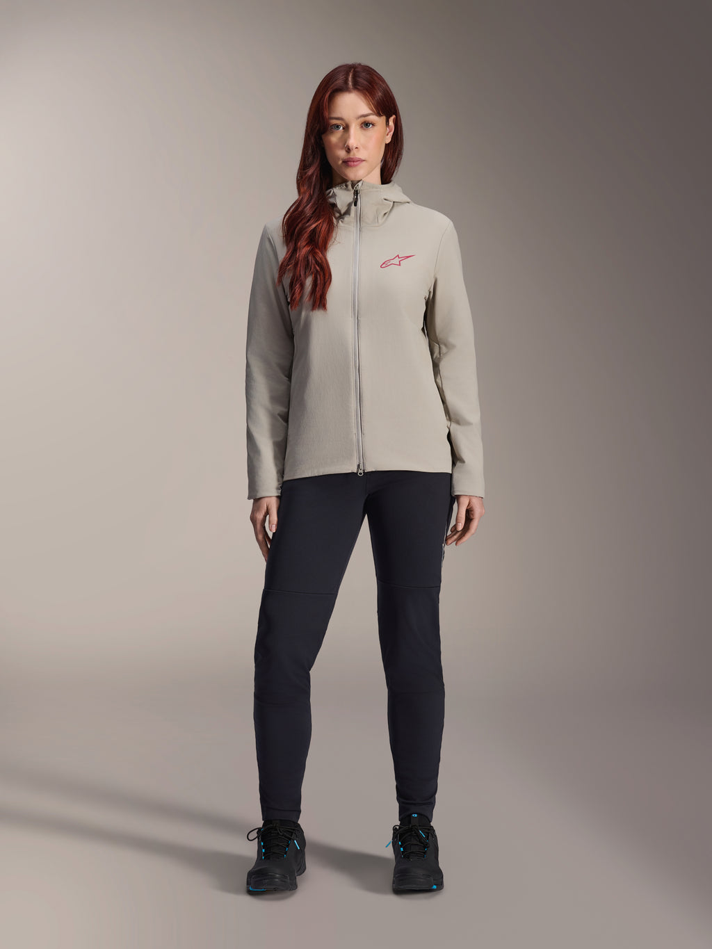 Alpinestars Stella A-Dura Thermal Jacket para mujer, chaqueta de ciclismo de montaña, gris titanio, usada con pantalones técnicos negros y calzado negro, con capucha forrada de vellón y logotipo rojo en el pecho, diseñada para montar en climas fríos