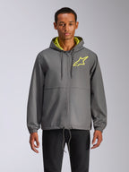 Chaqueta cortavientos Alpinestars Speeder Chromium, cortavientos gris carbón con capucha y logotipo de estrella en amarillo de alta visibilidad, interior de la capucha en verde lima, puños elásticos, cordones ajustables, cierre de cremallera frontal, estilo motorsport casual