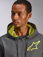 Chaqueta cortavientos Alpinestars Speeder Chromium, gris carbón con detalles en amarillo de alta visibilidad, con un logotipo de estrella amarilla en el pecho y forro de malla en la capucha a juego, cortavientos casual ligero