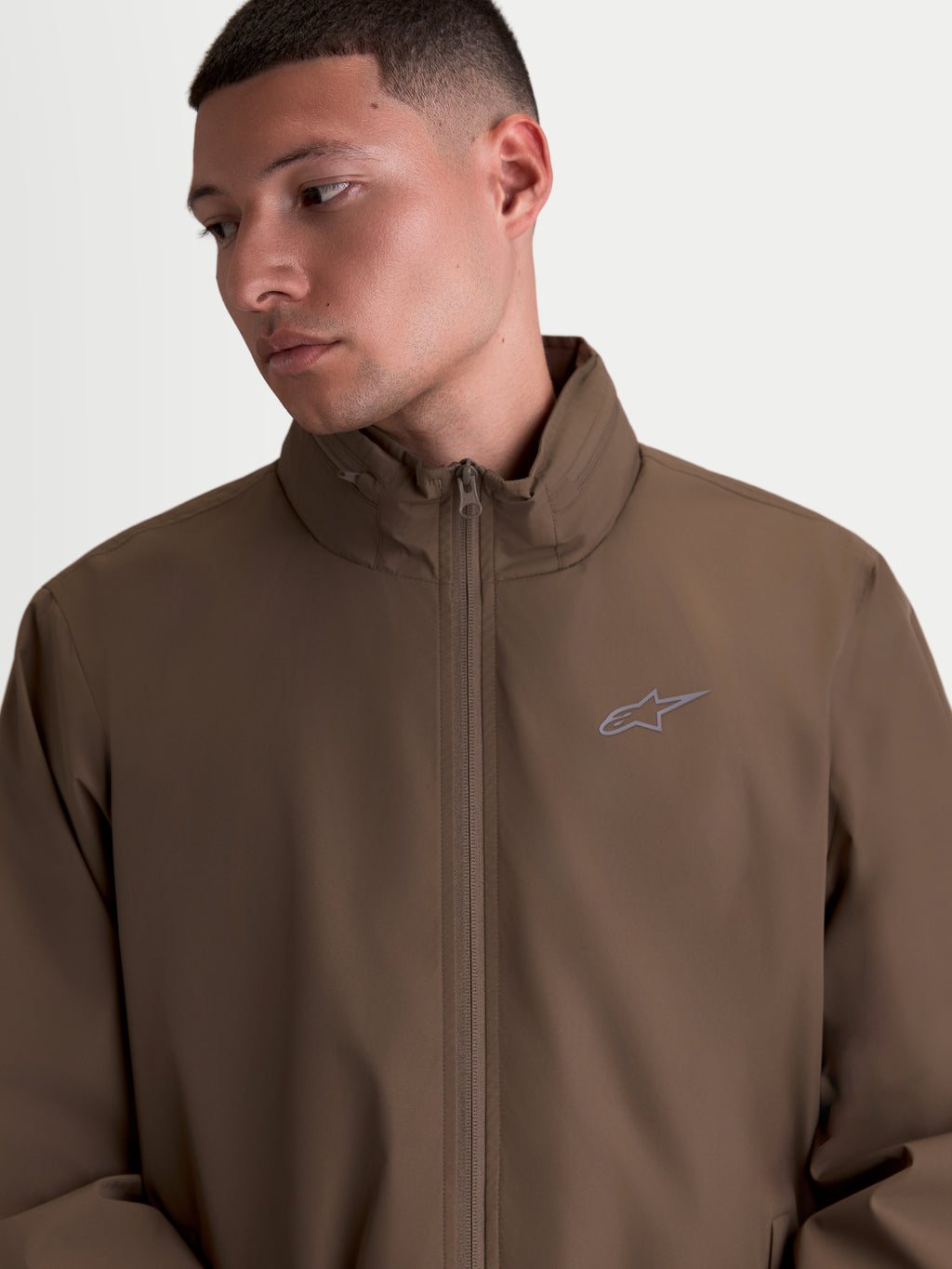 Alpinestars Overhaul Racer, chaqueta de sportswear ligera para hombre, color marrón, con cuello alto, cremallera frontal y pequeño logotipo Astars en el pecho, estilo inspirado en el motorsport.