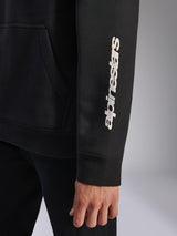 Sudadera con capucha Harken de Alpinestars, negra, primer plano de la manga con logotipo vertical blanco, puño de canalé y detalle del bolsillo canguro, forro polar deportivo casual