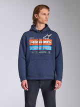 Alpinestars Harken Hoodie, ropa urbana casual, azul marino con gráfico 'Racing Ahead' en el pecho en naranja y azul claro, sudadera de forro polar con bolsillo canguro y capucha con cordón, lucida por un modelo con vaqueros oscuros